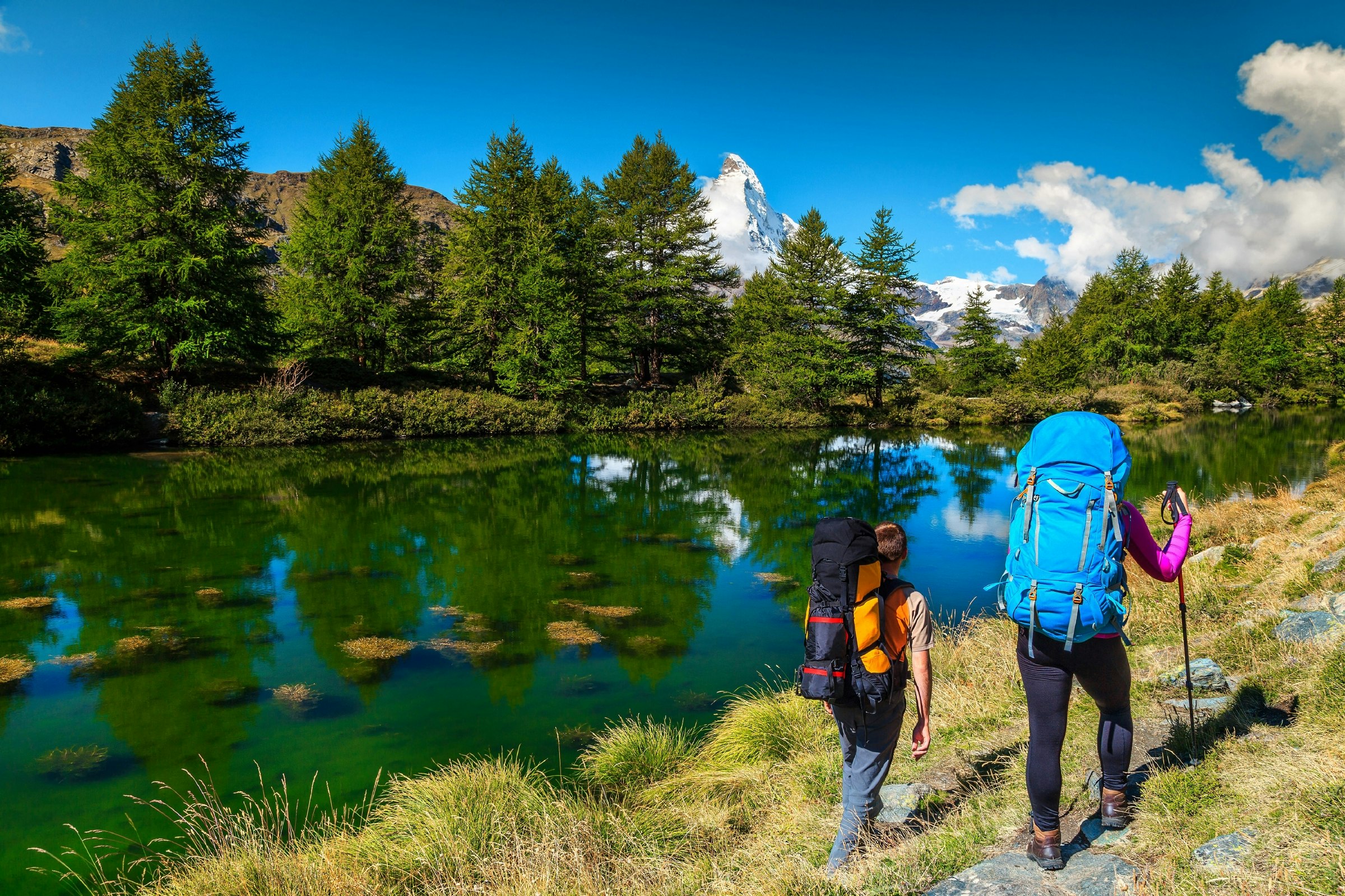 Two hikers with backpacks near the Grindjisee alpine lake in Zermatt.