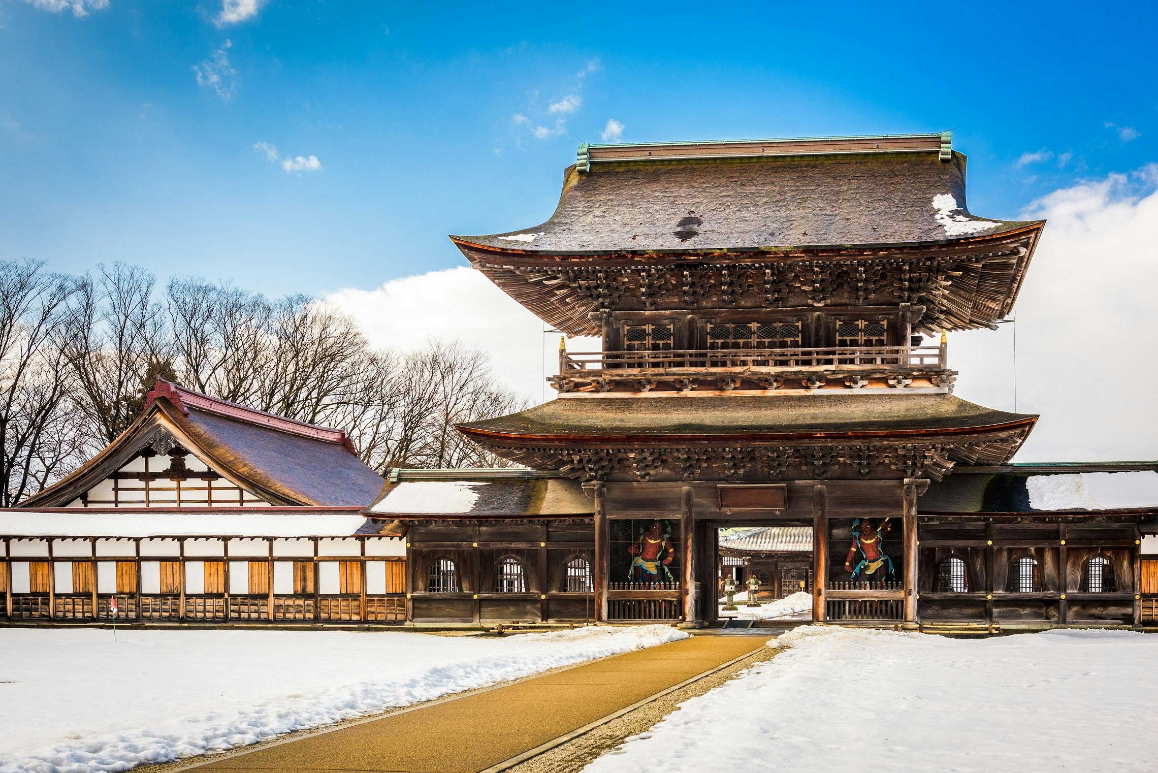 Ett högt och stort trätempel, med ett traditionellt japanskt lutande tak.  Marken runt templet är täckt av snö.