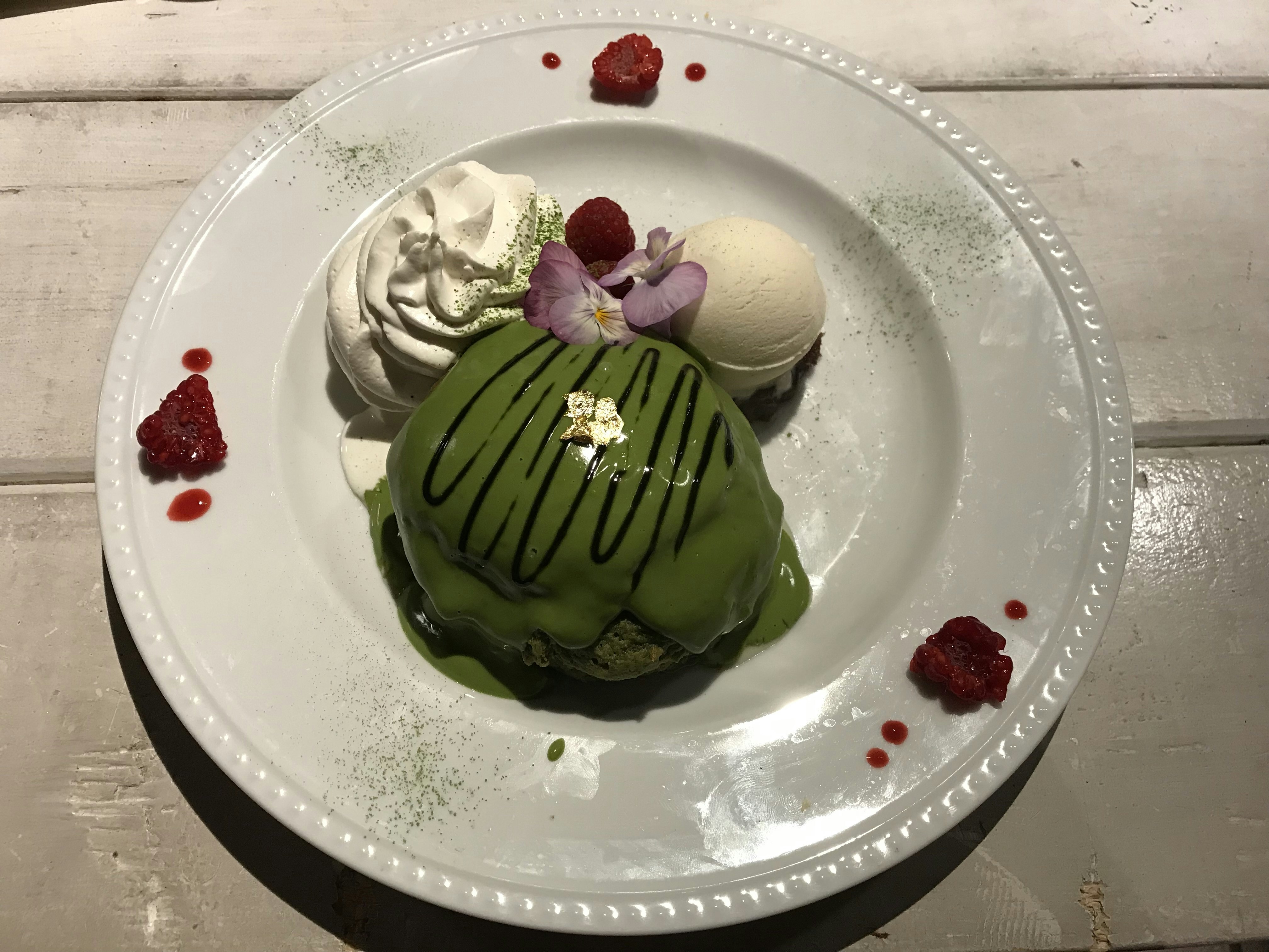 A delicately presented plate of matcha pancakes, covered in a a green sauce, alongside a rosette of whipped cream and a scoop of ice cream at Ain Soph Journey, Kyoto.