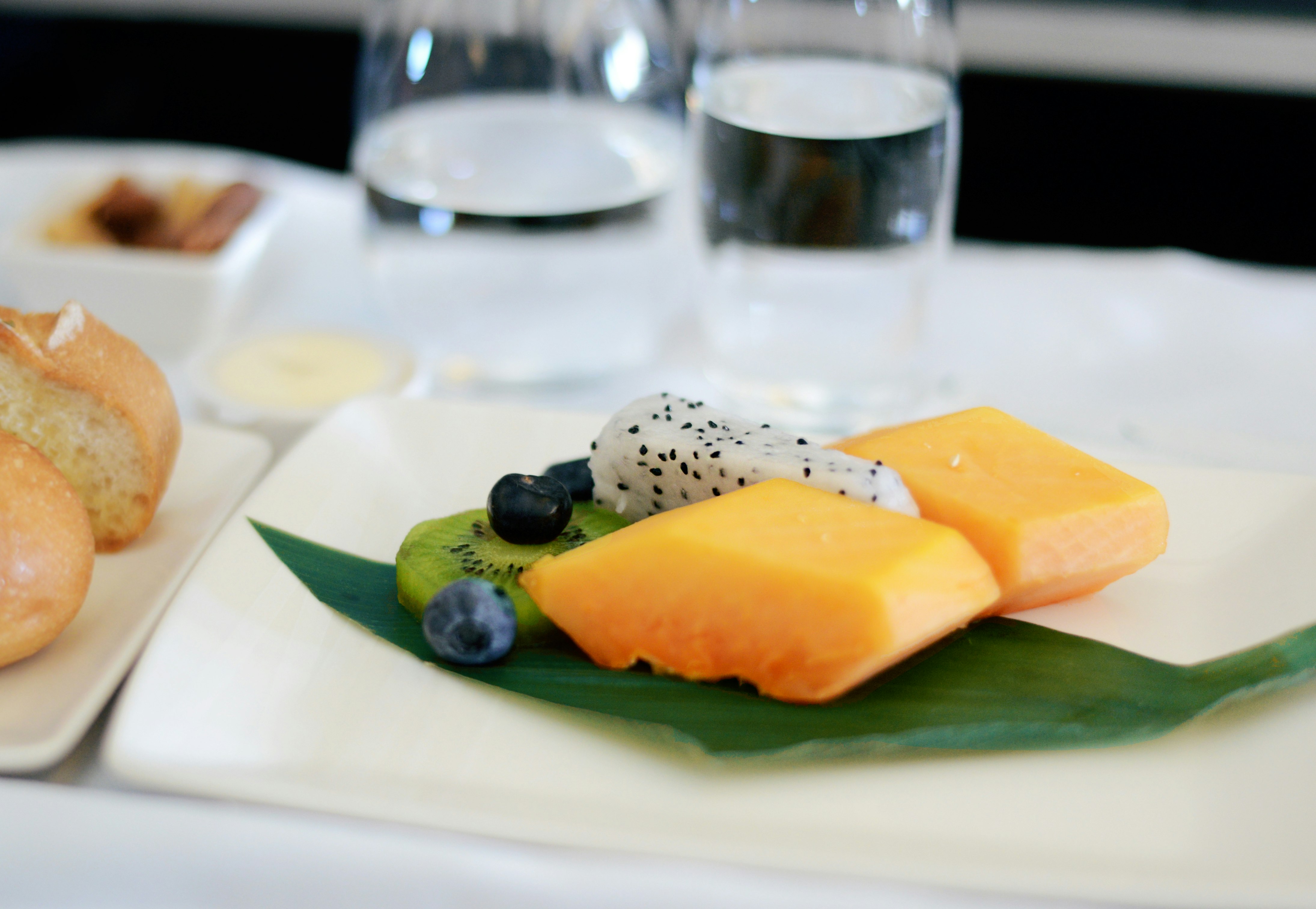 A fruit salad sits on a airline tray plate. 