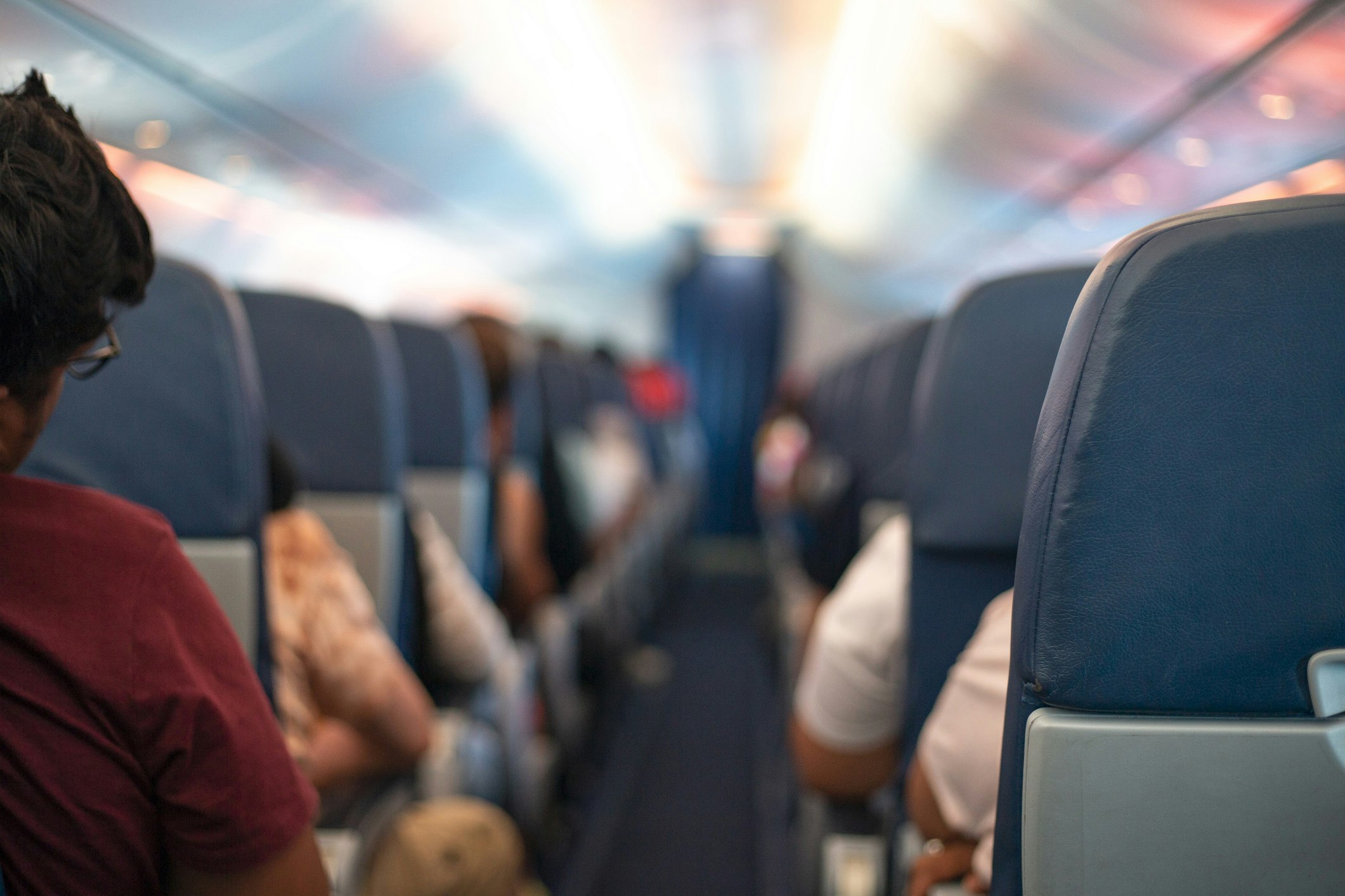 The interior of an airline cabin, looking down the aisle.