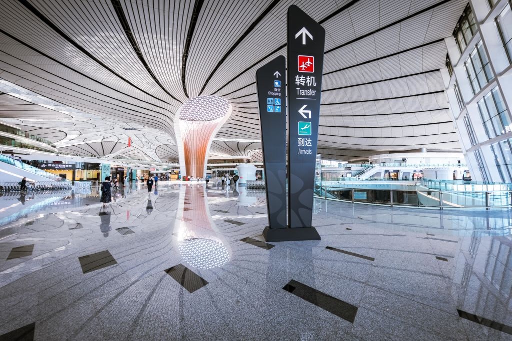 A sign shows passengers where to go for arrivals and transfers inside a new futuristic airport. 
