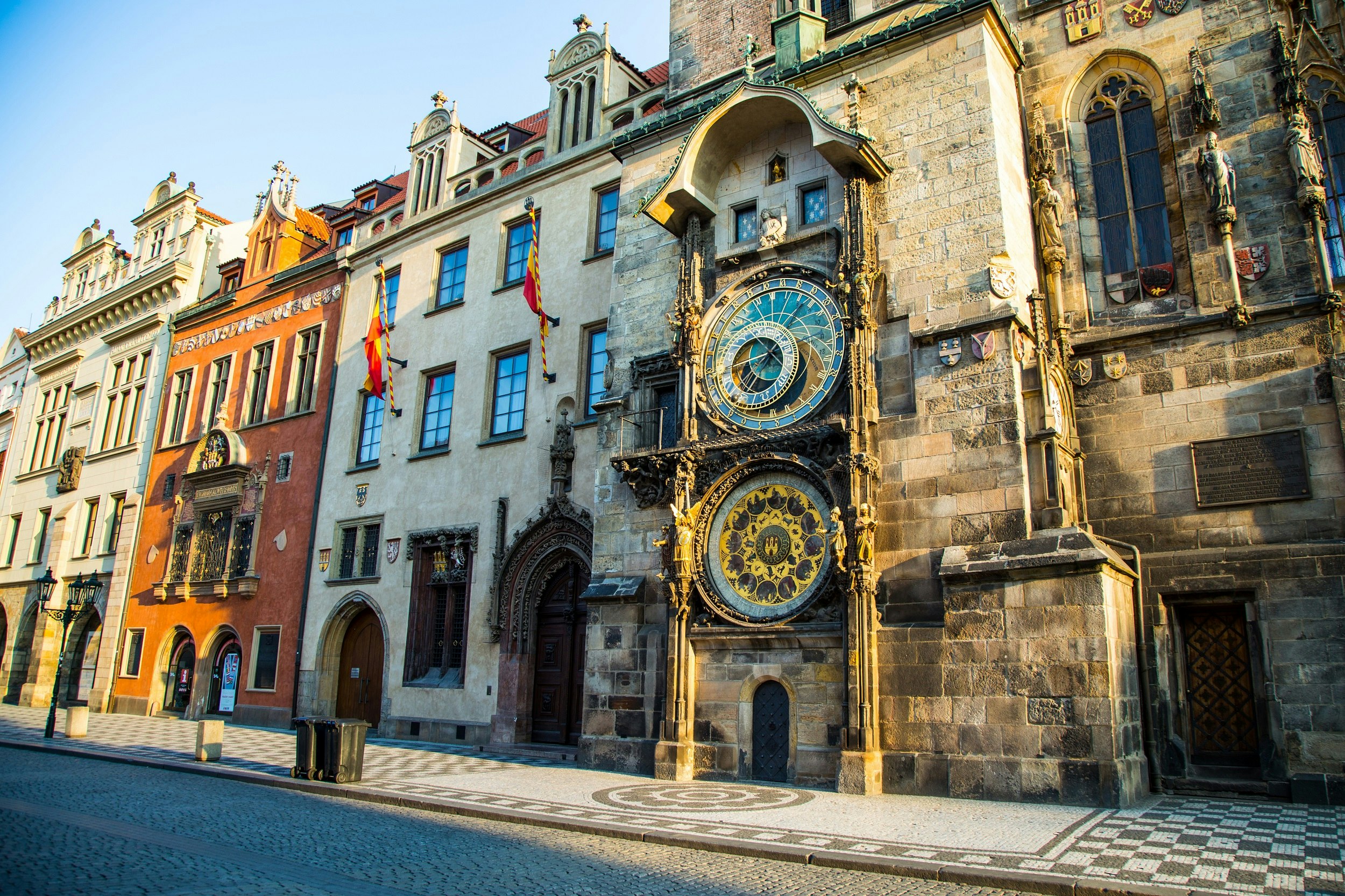 A large astronomical clock with several faces covers the side of a three-storey building