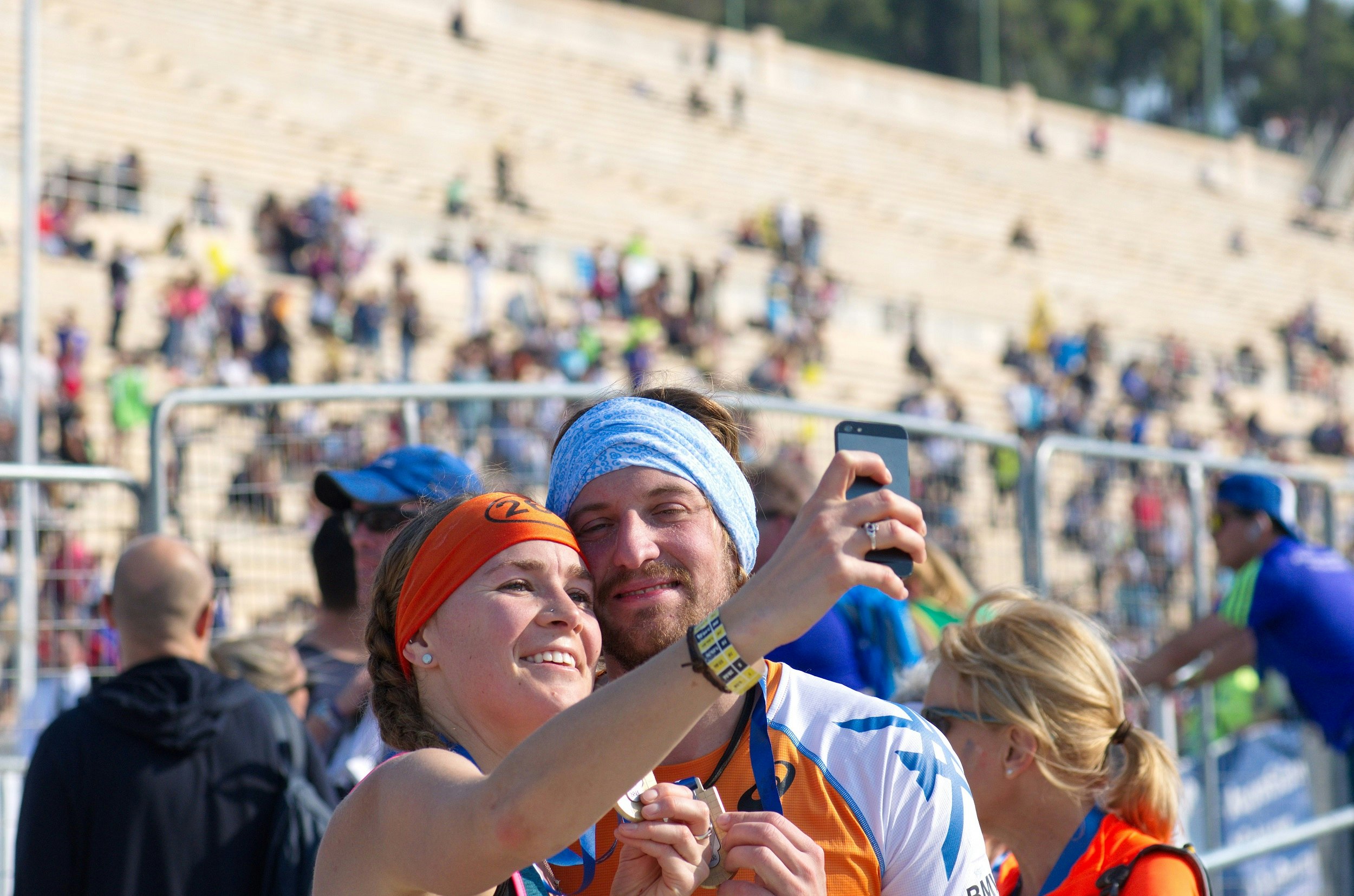 Happy couple taking a selfie after finishing the 33rd Athens Classic Marathon; in the background are the stone stands of the Panathenaic stadium or kallimarmaro (site of the first modern Olympiad in 1896)
