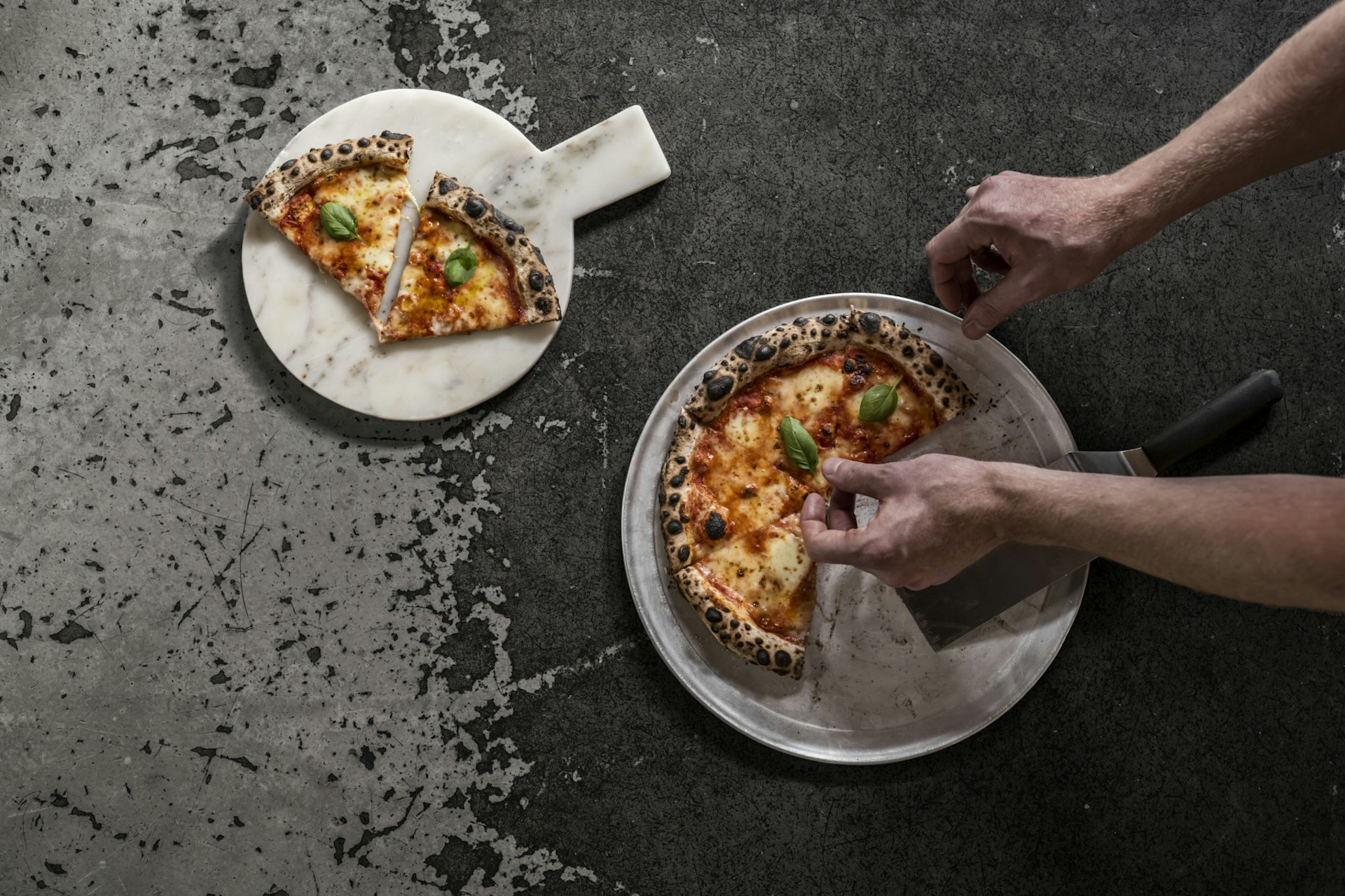 A picture of a pizza being cut into slices with a pizza roller and arranged on a display plate