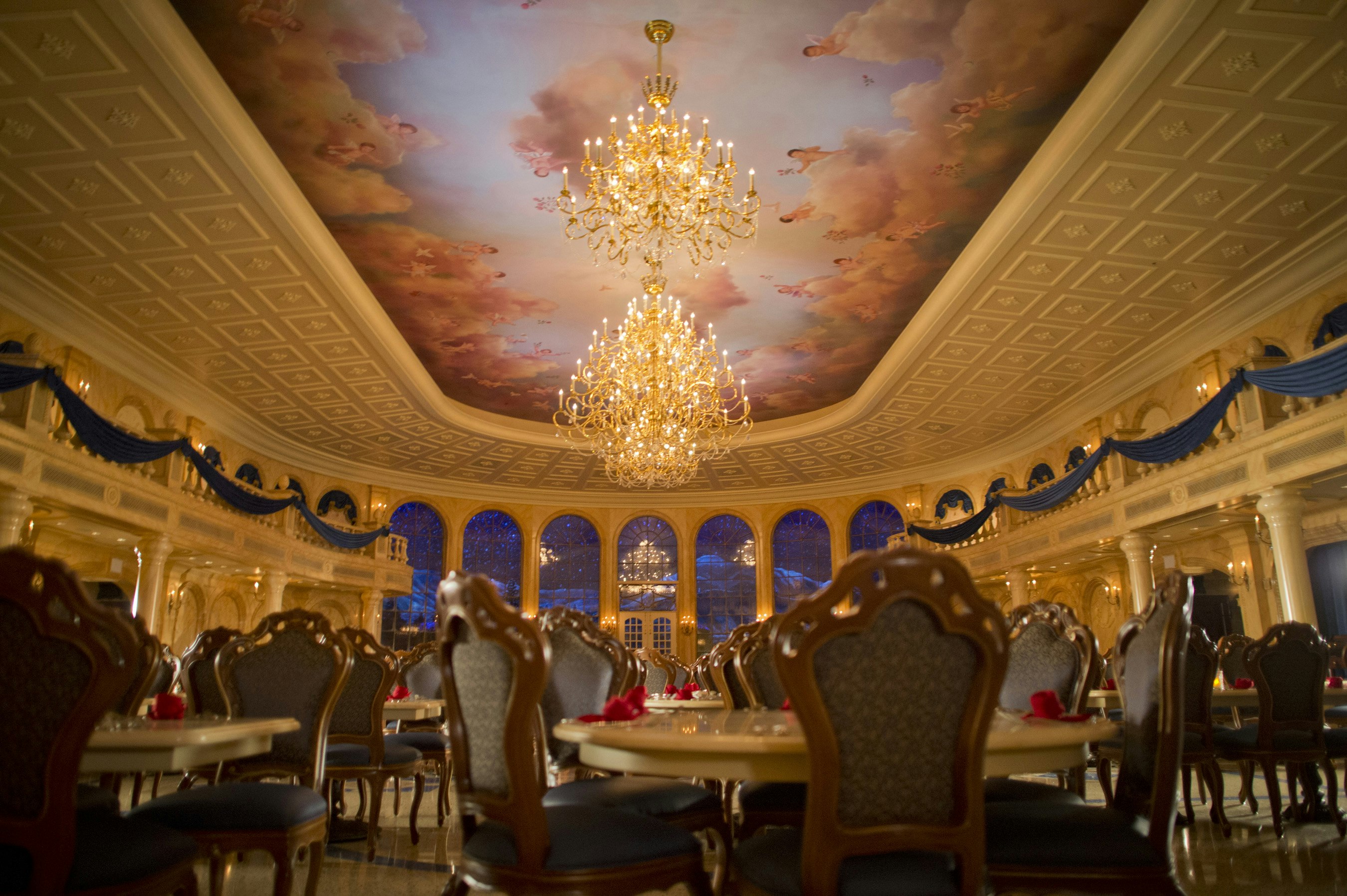 A replica of the ballroom from Disney's Beauty and the Beast, including high ceiling with clouds and cherubs painted on it and a sparkling chandelier
