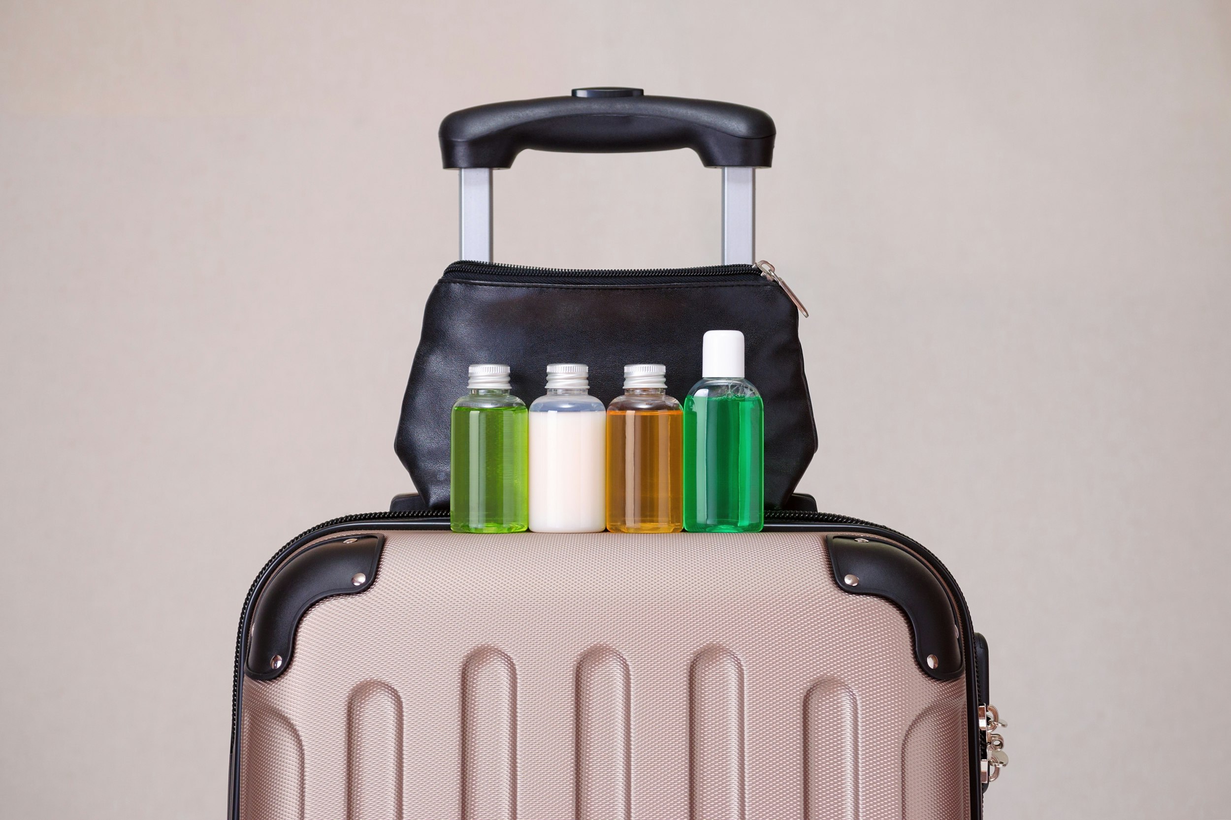 Beauty products in travel containers sitting on a suitcase