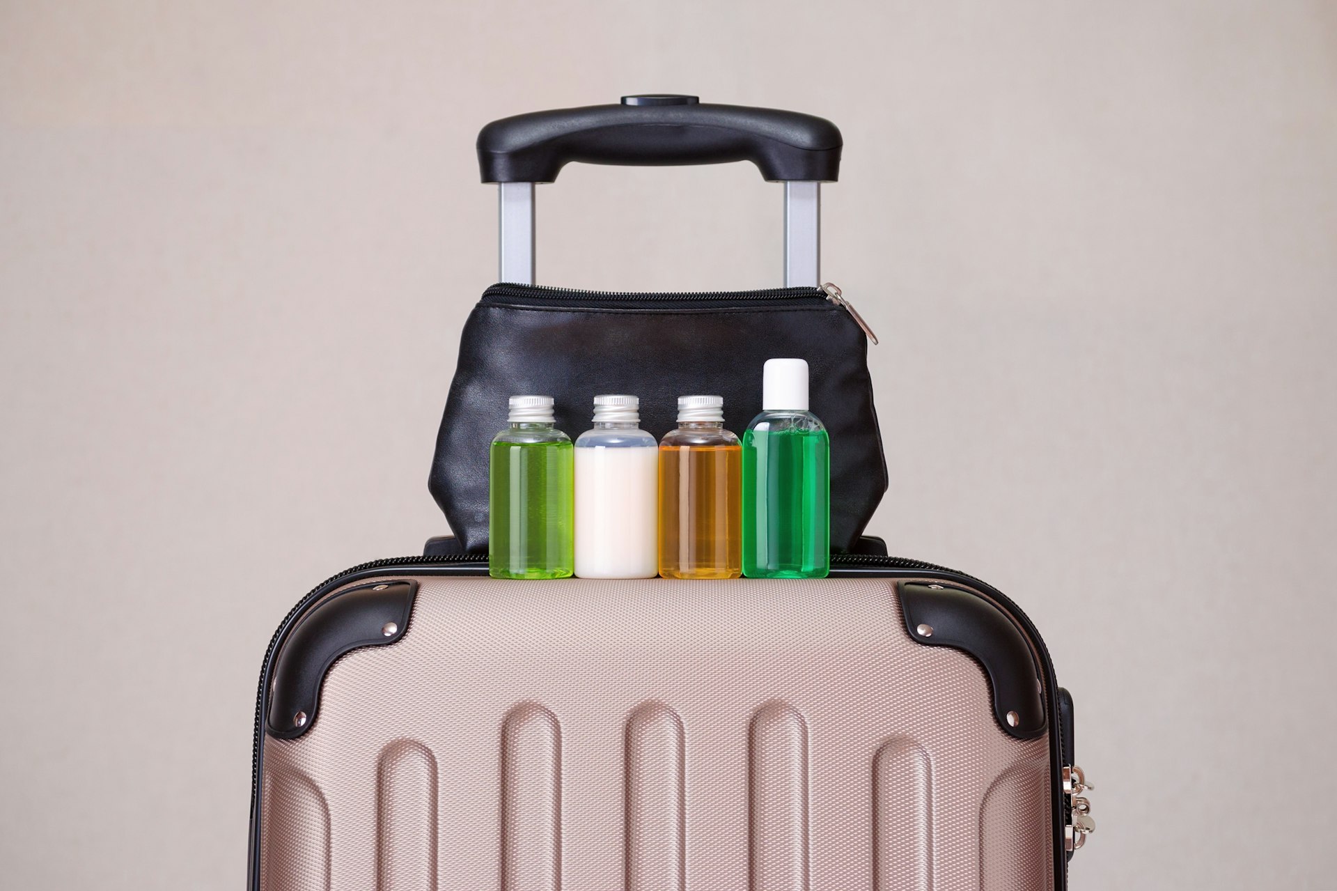 Beauty products in travel containers sitting on a suitcase