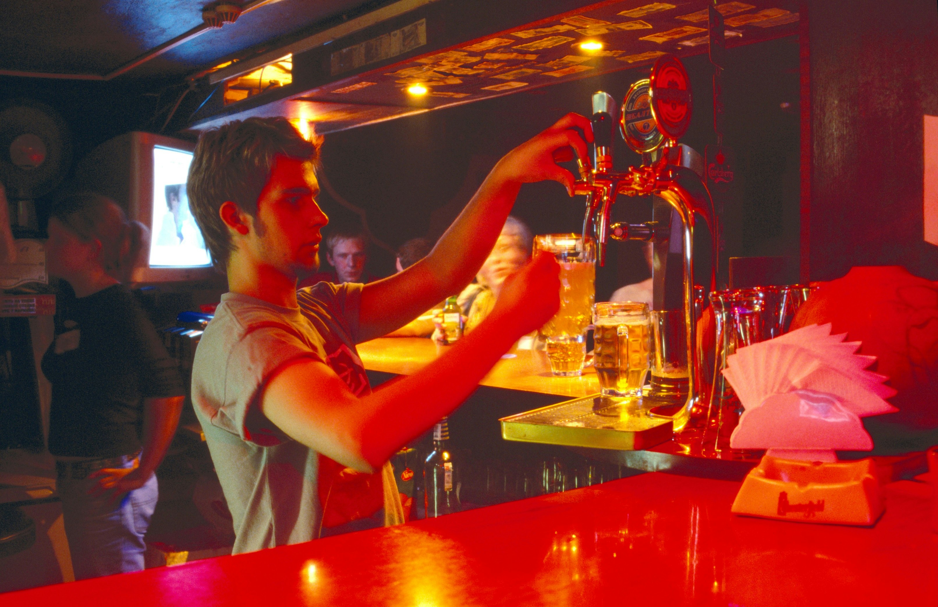 A barman pours a beer from a tap in a dimly lit bar in St Petersburg.