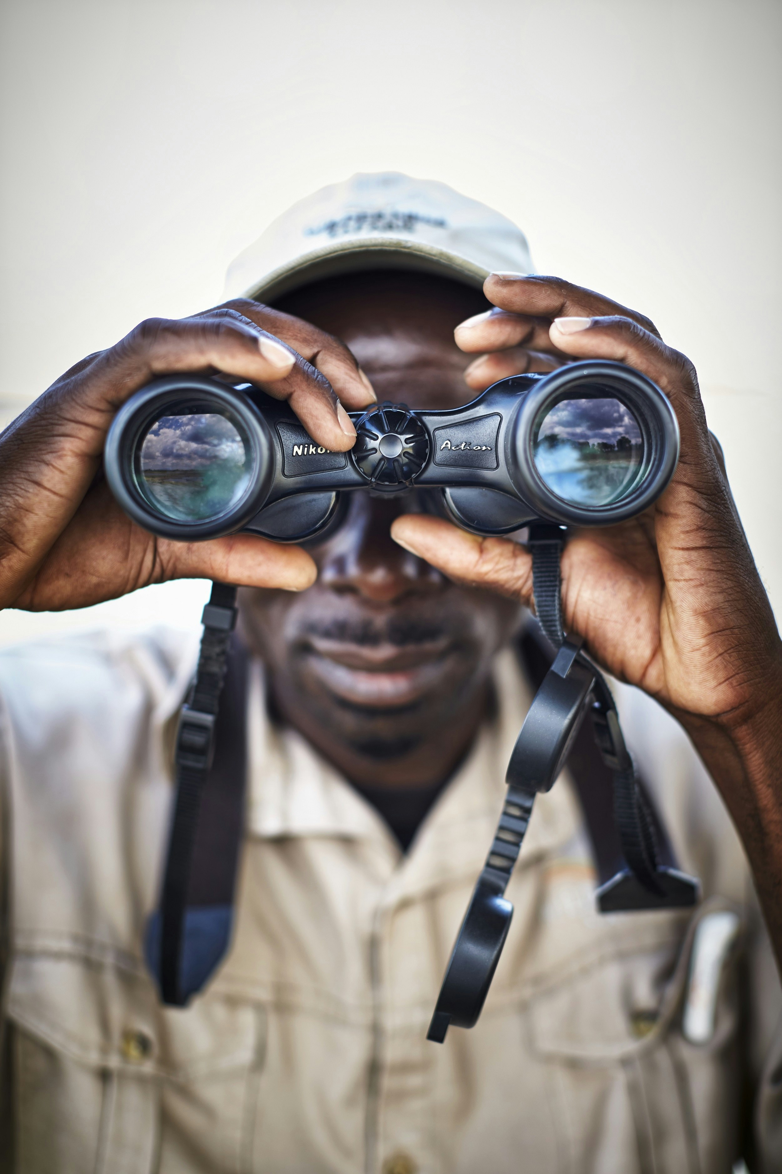 A man is staring directly into the camera's lens with a huge pair of black binoculars.