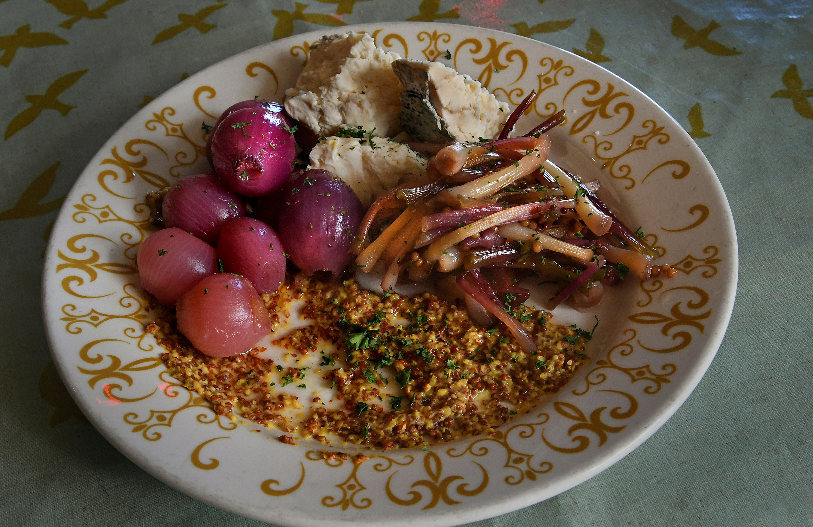 A white plate rimmed with an ornate gold design is filled with colorful vegetables in a farm to-table dish at Bluegrass Kitchen in Charleston, West Virginia