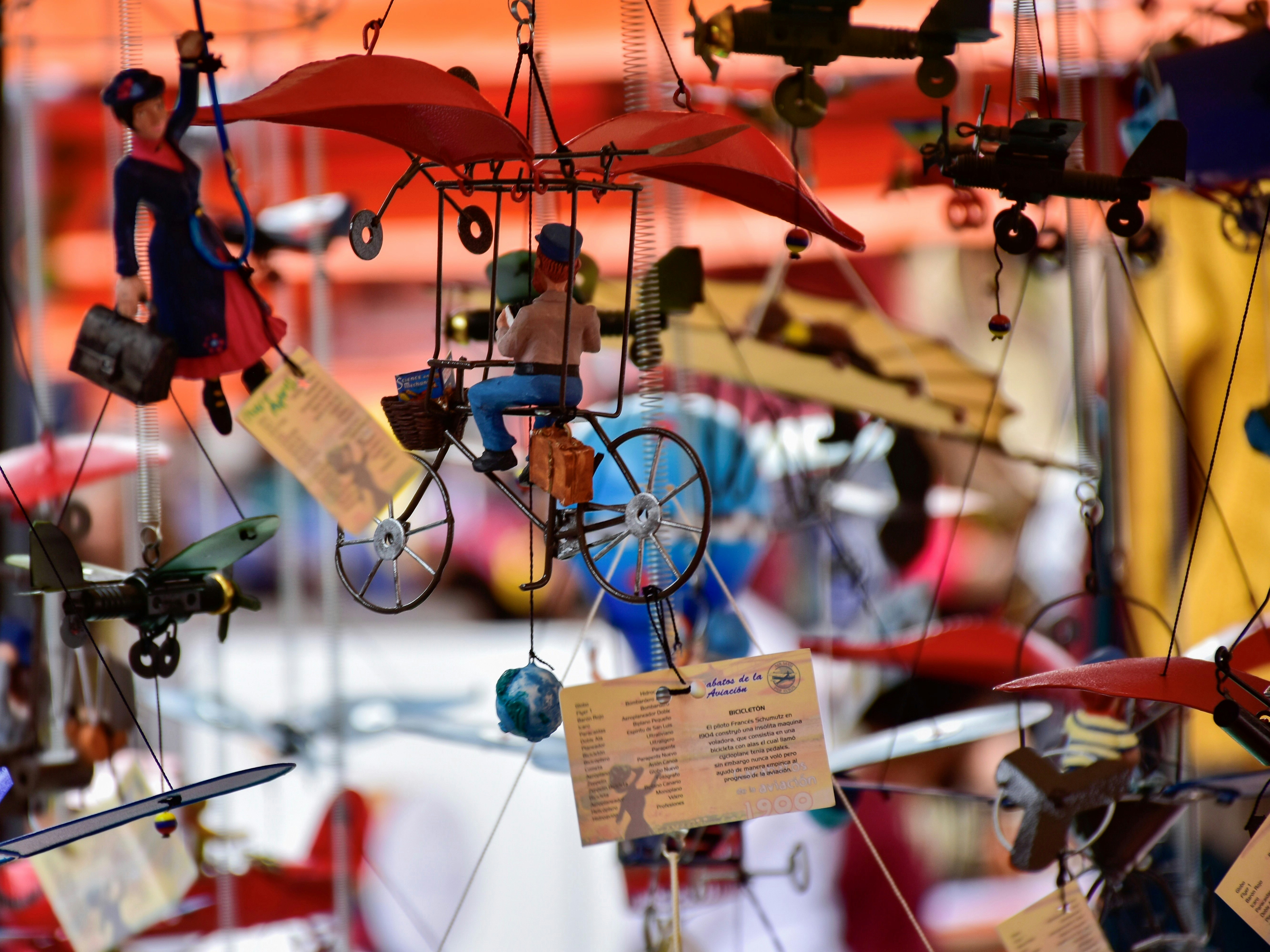 A display of hand-made puppets and other toys including a Mary Popppins figure, a man on a bicycle, airplanes, etc hang at the Usaquen Park Sunday Craft Fair in Bogota Columbia