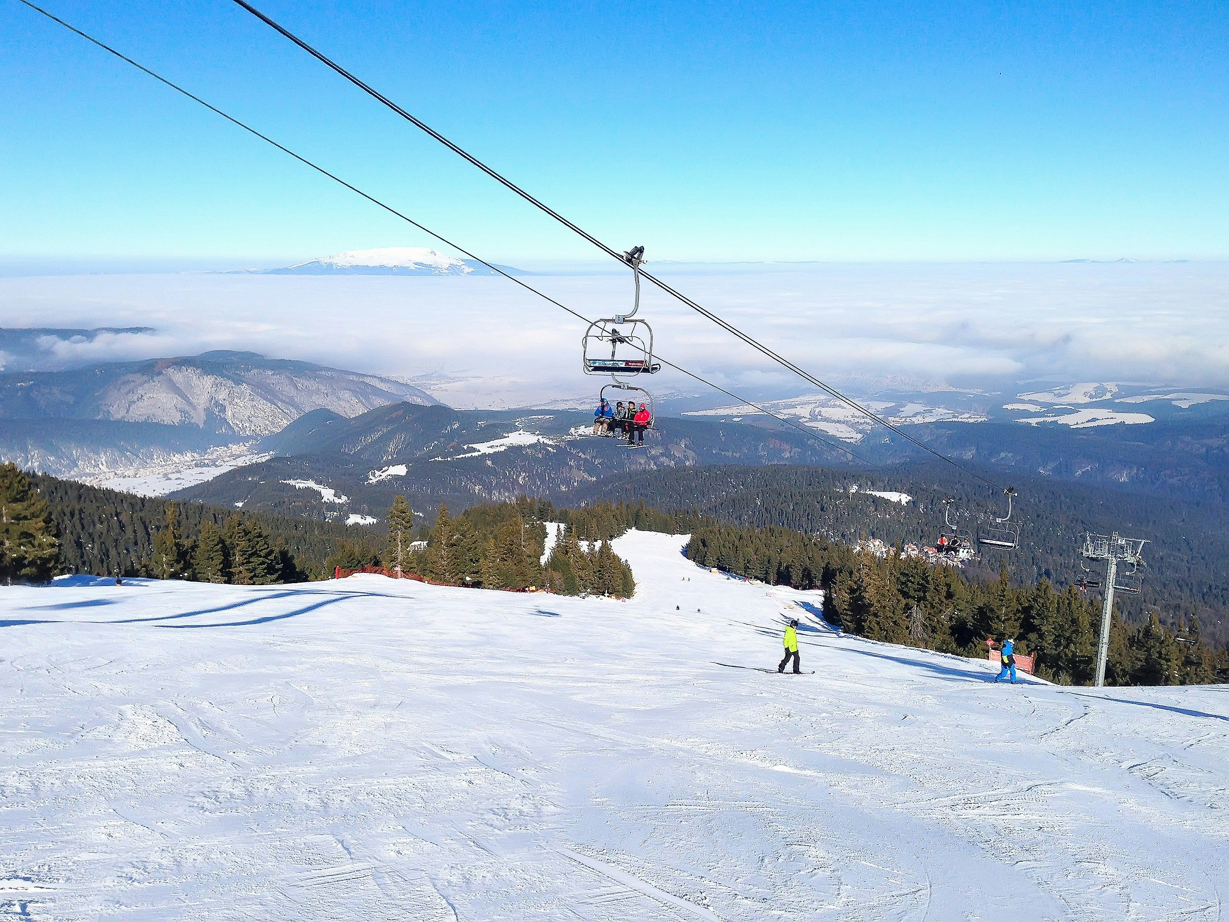 A ski slope covered in snow, with a chairlift passing overhead.