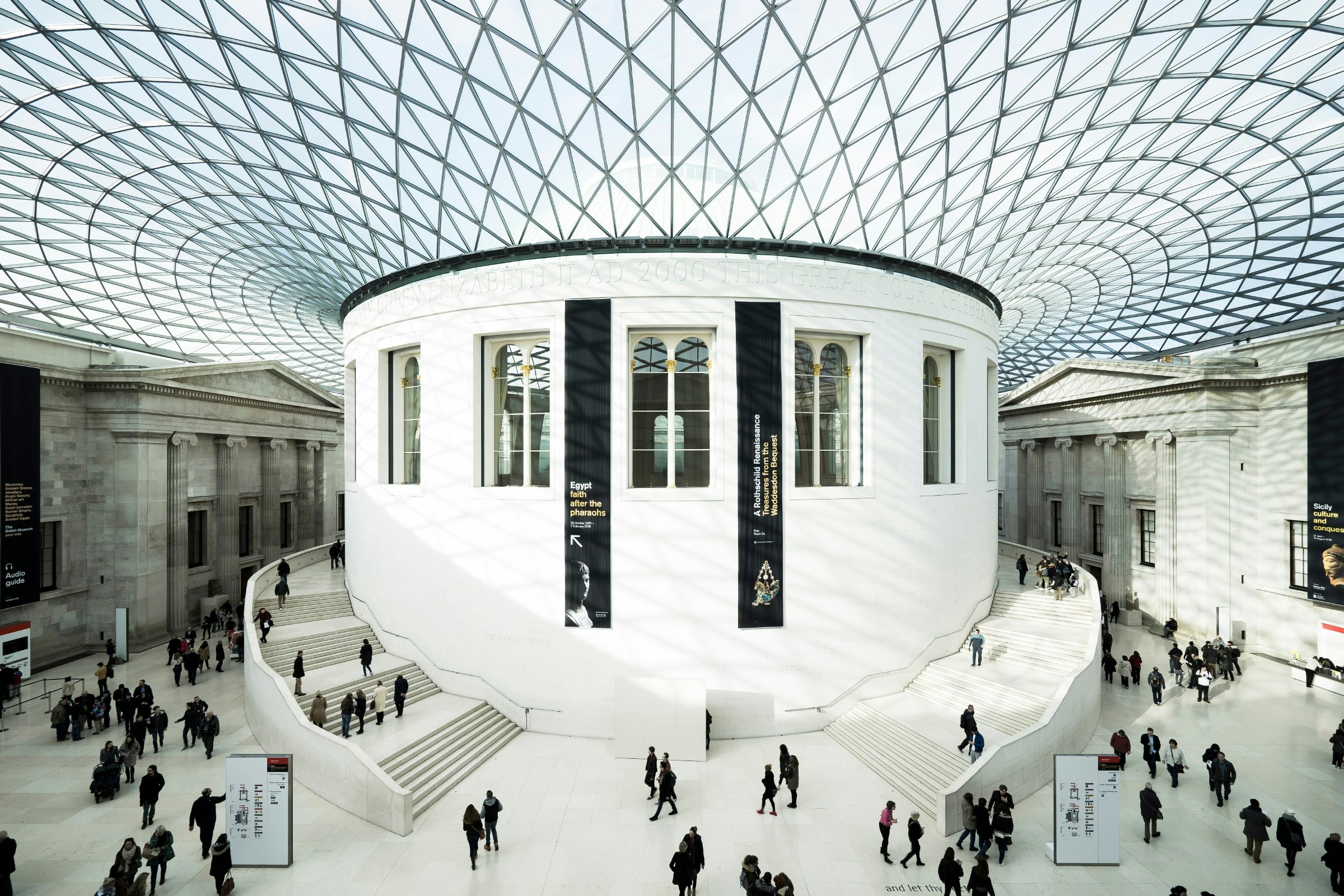 Sun illuminates the Great Court of the British Museum in pure white as it dives through the glass roof onto visitors who, lithe like L. S. Lowry's great subjects, climb the circular stairs or mill around on the ground floor