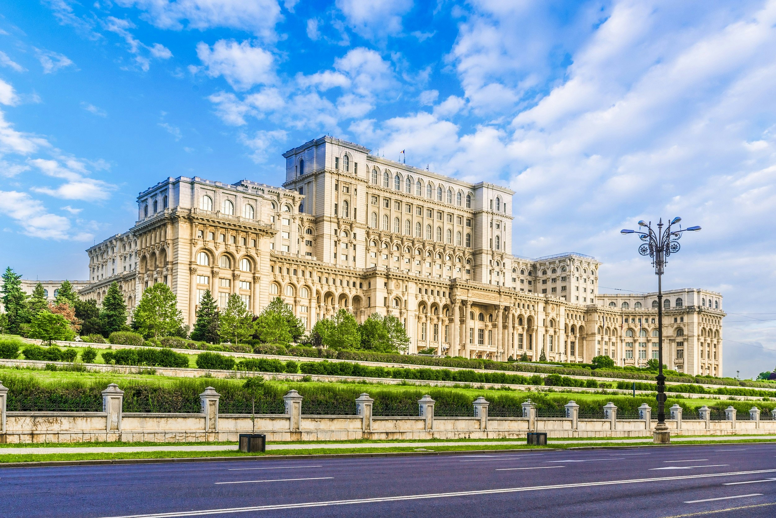 A huge marble building with several tiers and hundreds of windows in landscaped gardens.
