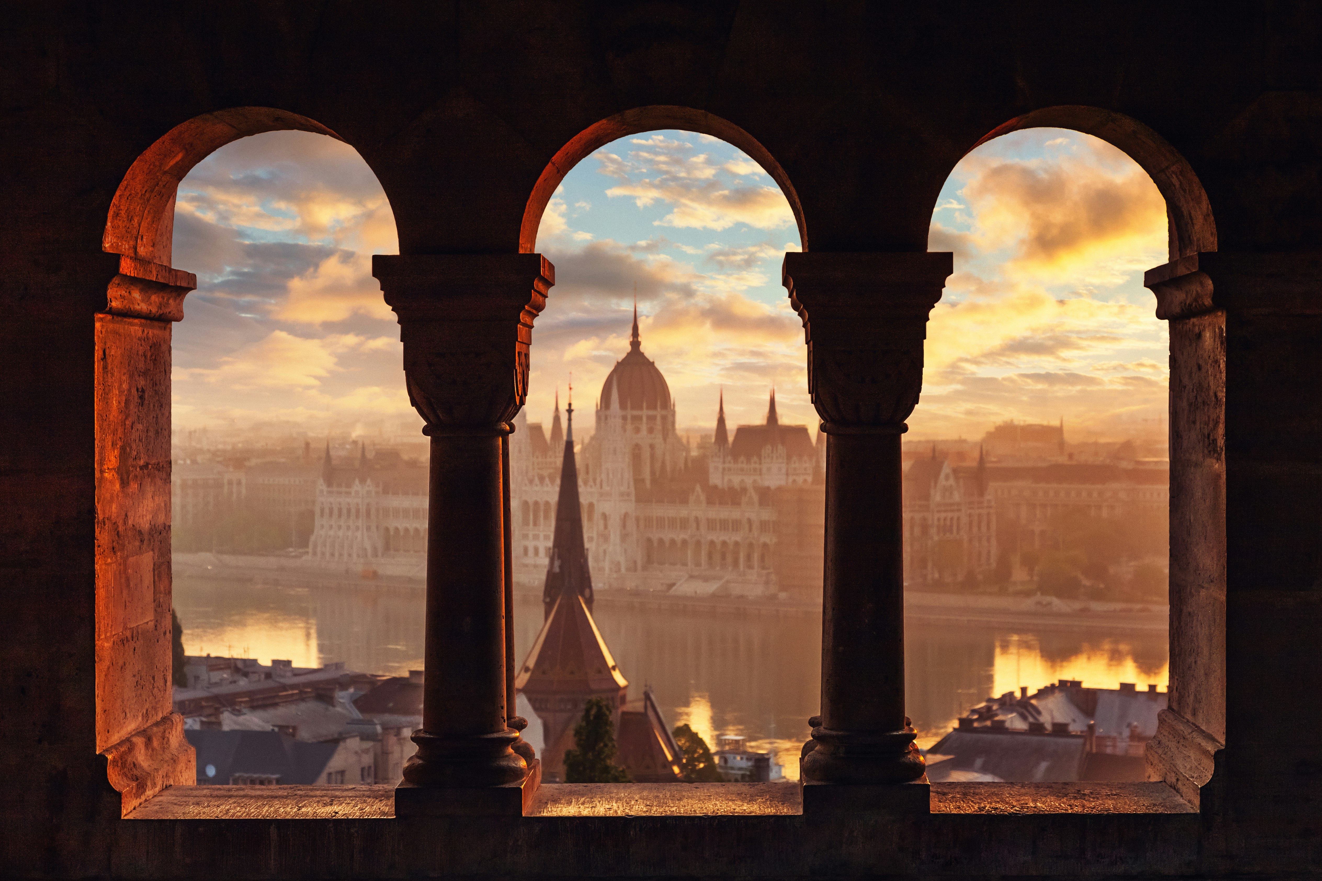 A view of a Hungardian Parliament building through columns. 