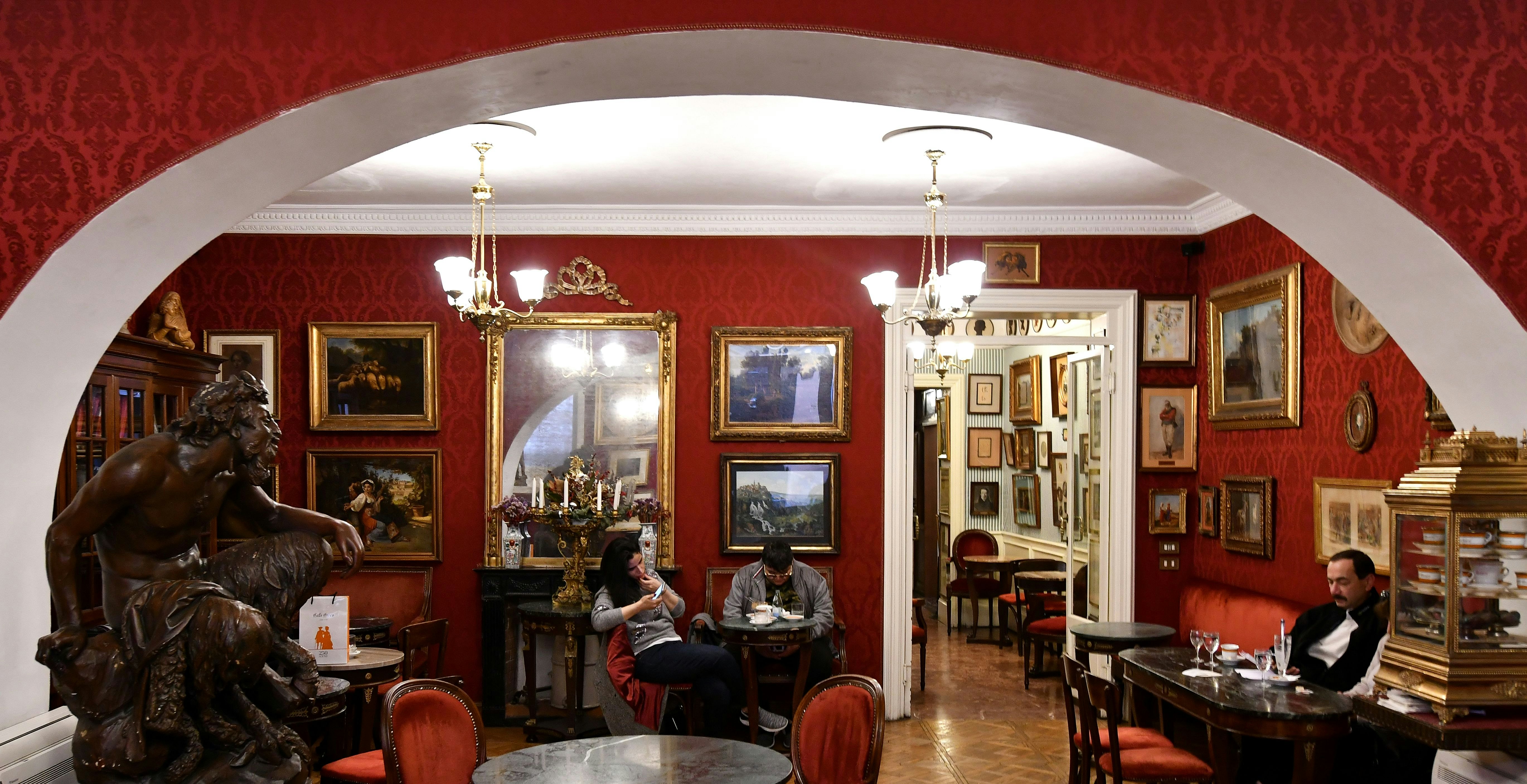 A wide shot of the interior of Caffé Greco with its iconic red walls