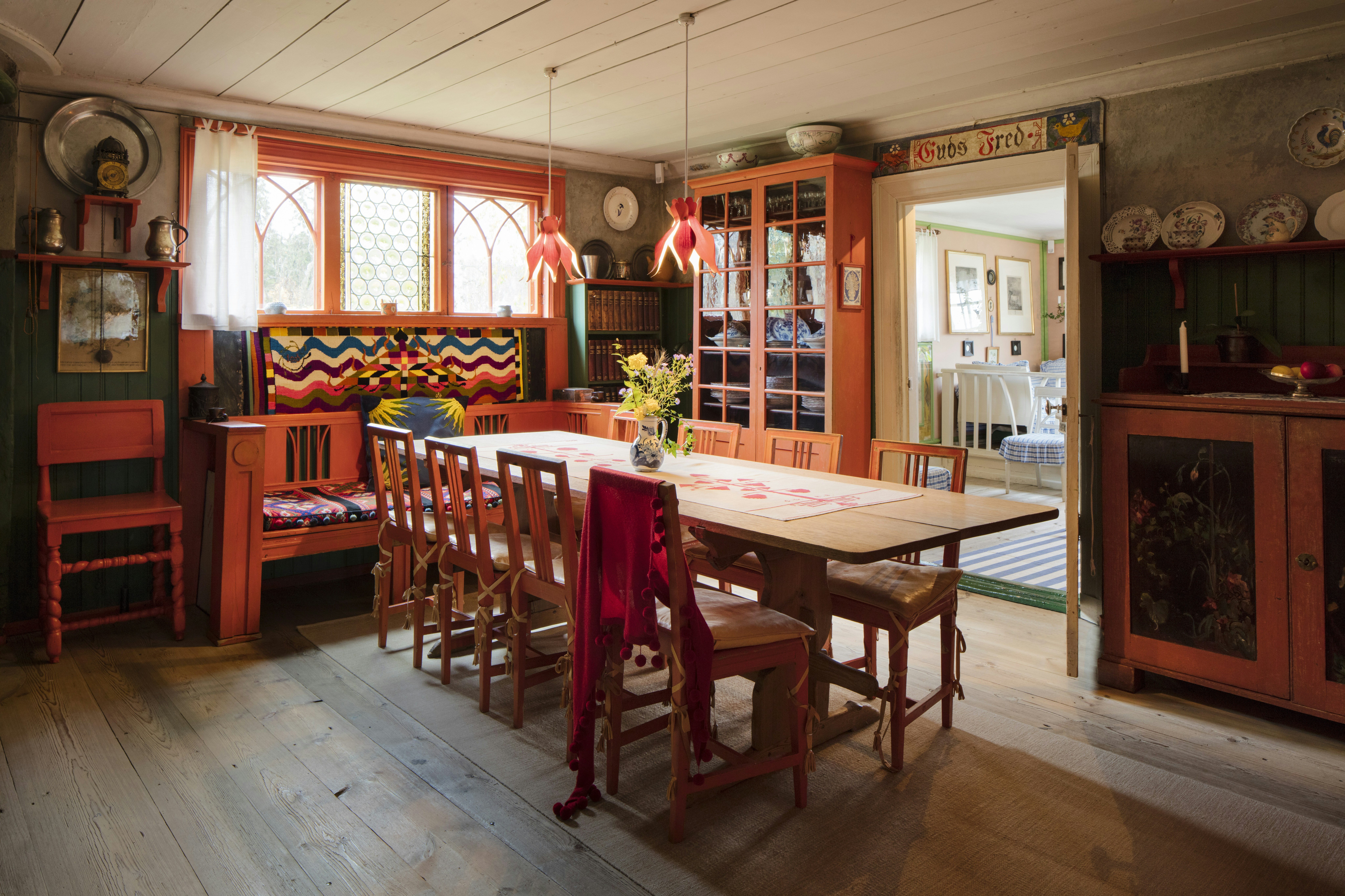 The dining room at  Carl Larsson-gården; there is a long dining table surrounded by simple wooden chairs, and two wooden sideboards.