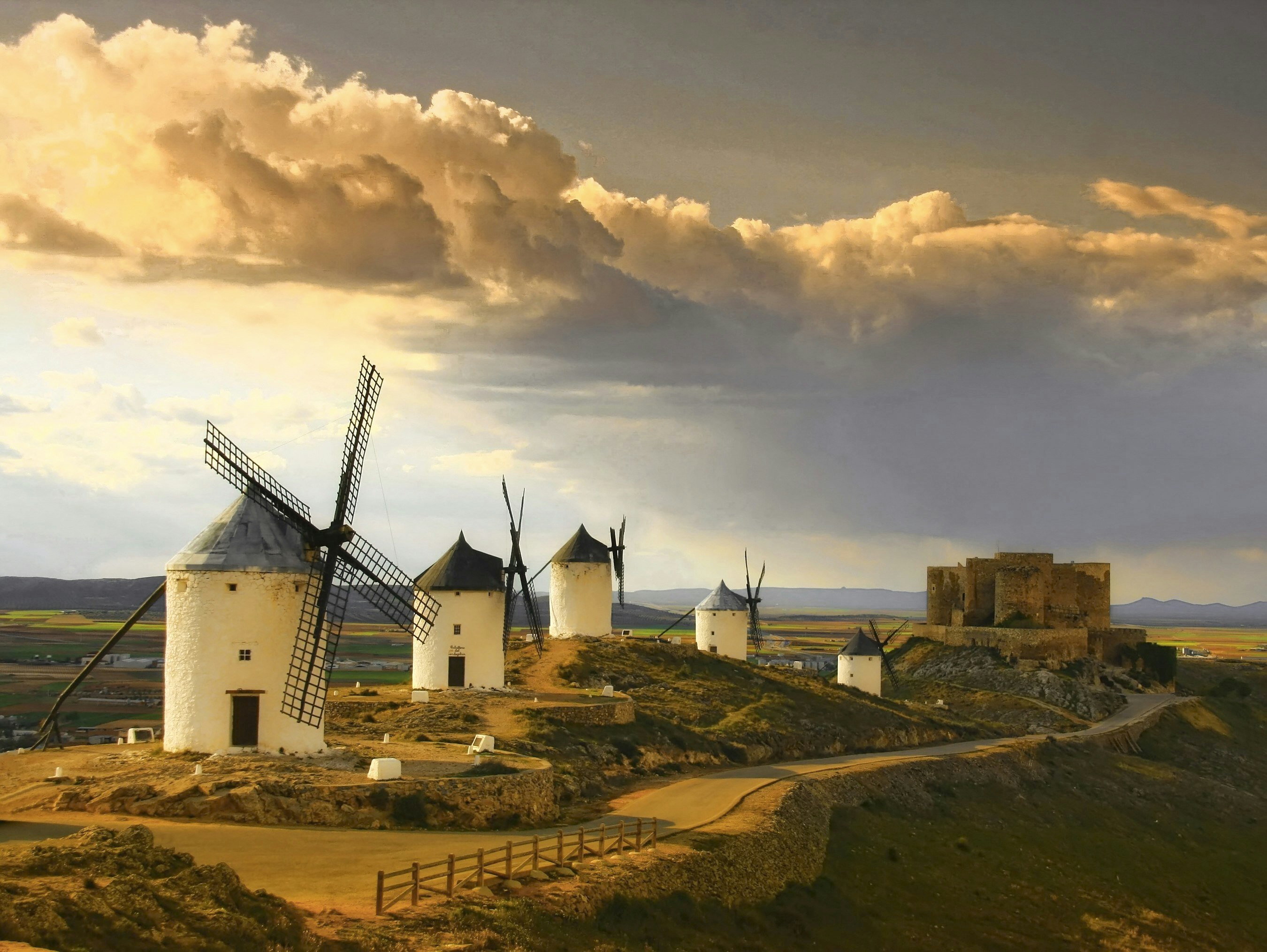 White cylindrical windmills dot a warm-hued plateau at Castilla la Mancha in the Cabañeros region of Spain