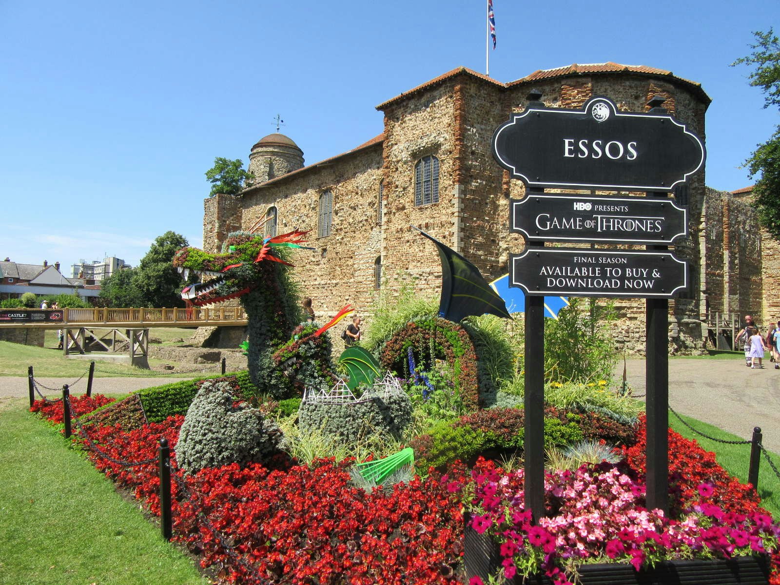 A topiary dragon with a sign advertising HBO's Game of Thrones with Colchester Castle in the background