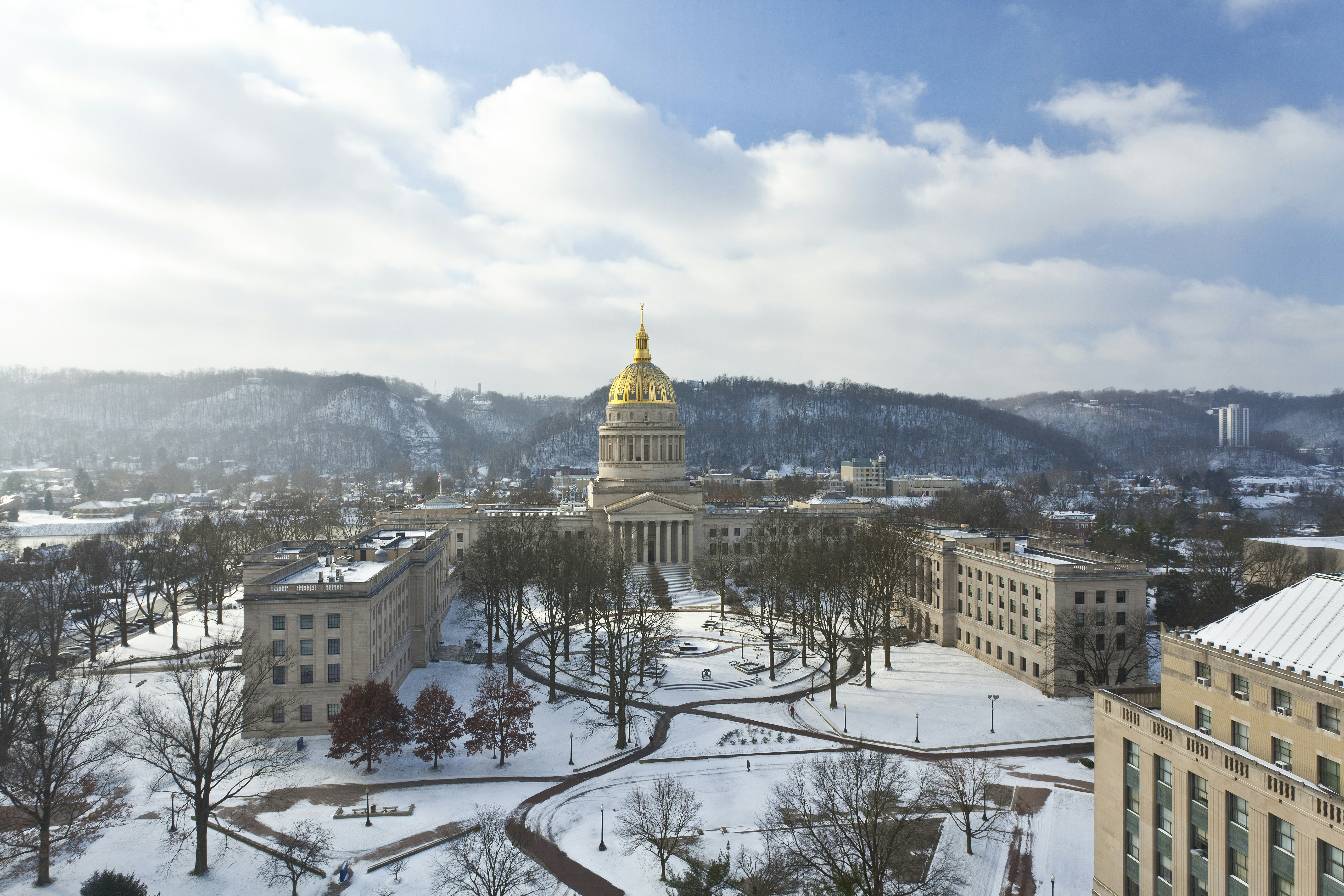 The gold dome of the West Virginia State Capitol building and surrounding campus under a blanket of snow. 