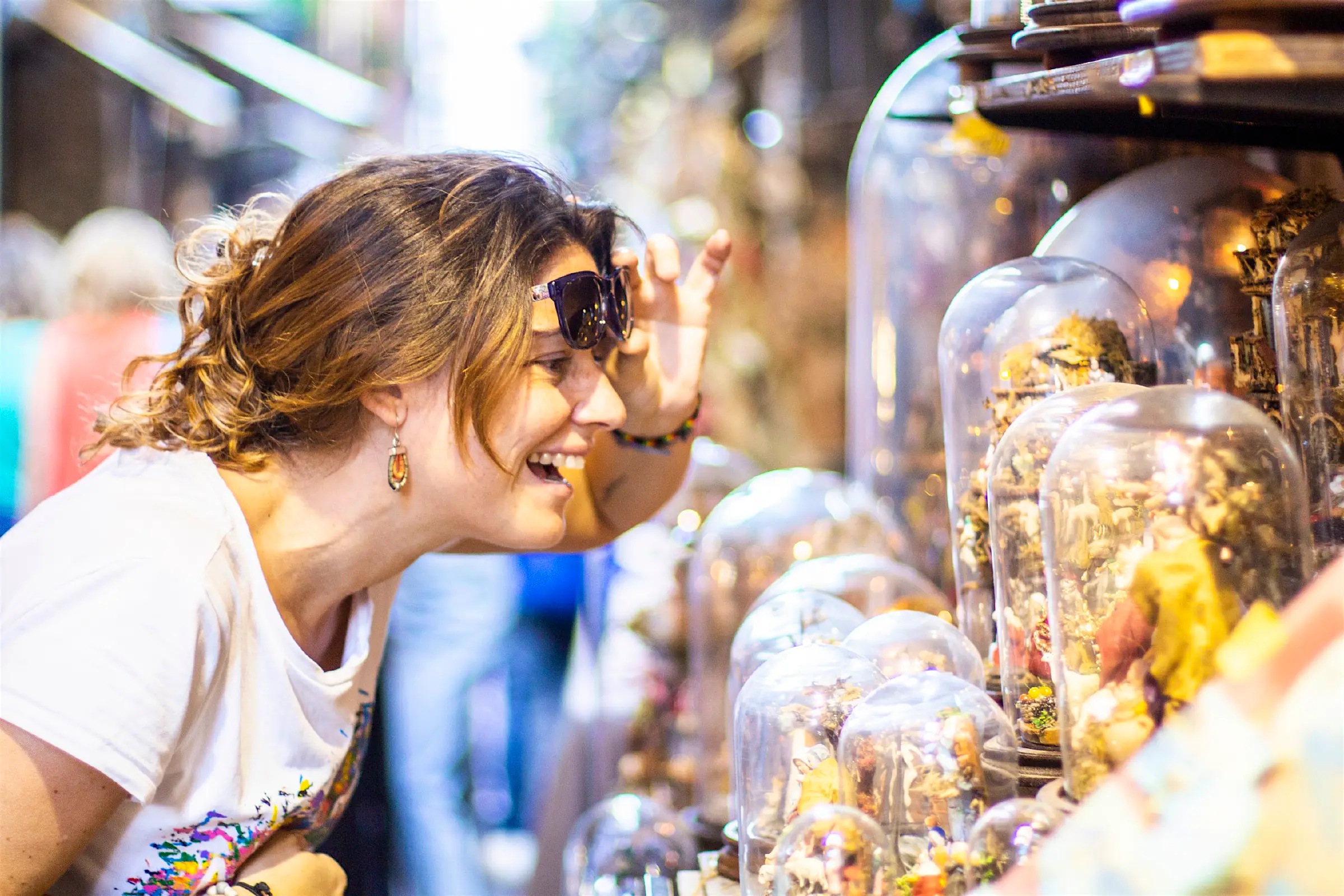 cheap activities for solo travellers.jpg Smiling woman looking at glass-domed items at a street market in Naples.