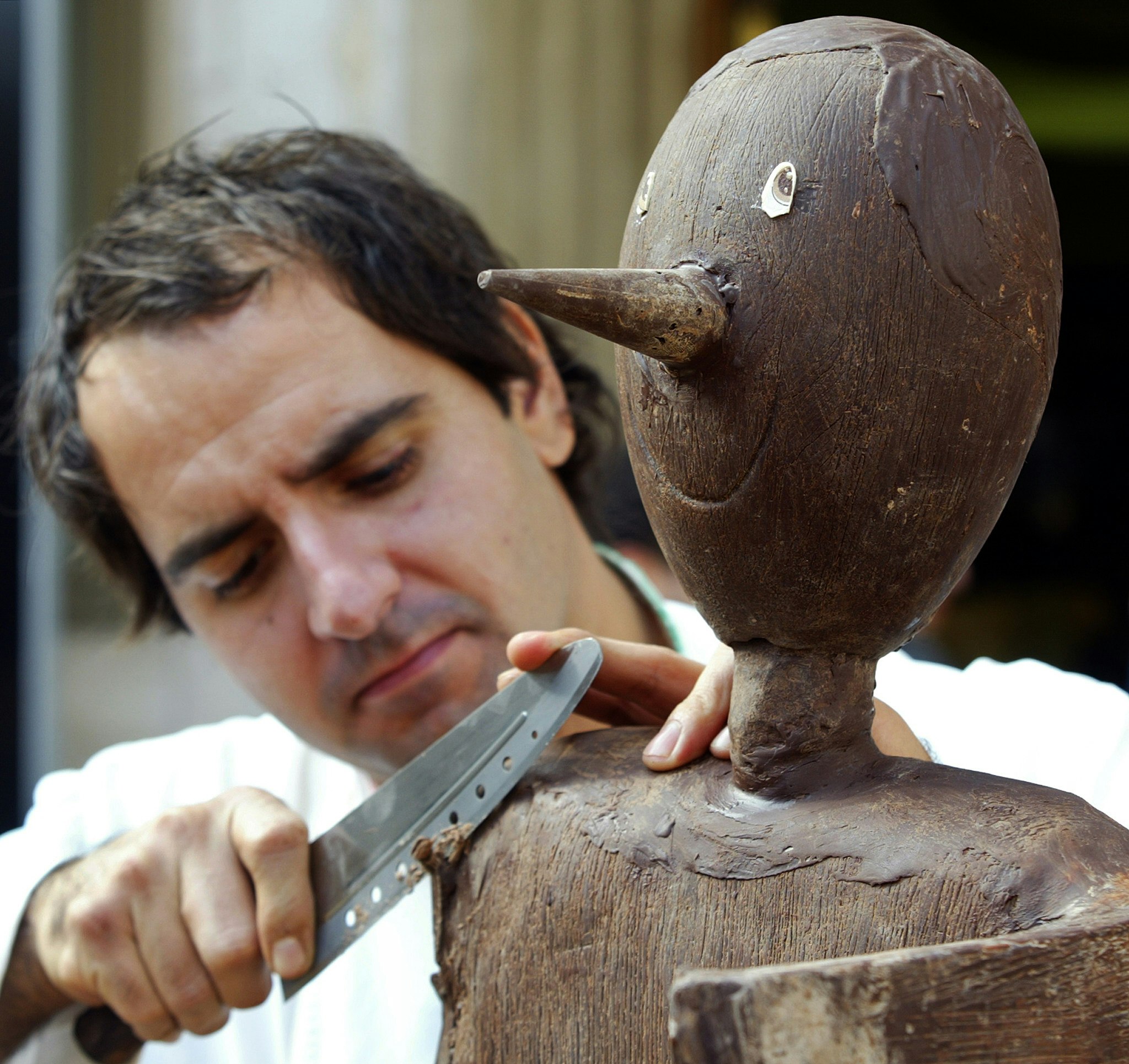 A picture of a sculptor during Eurochocolate festival carving out a Pinocchio from a block of chocolate