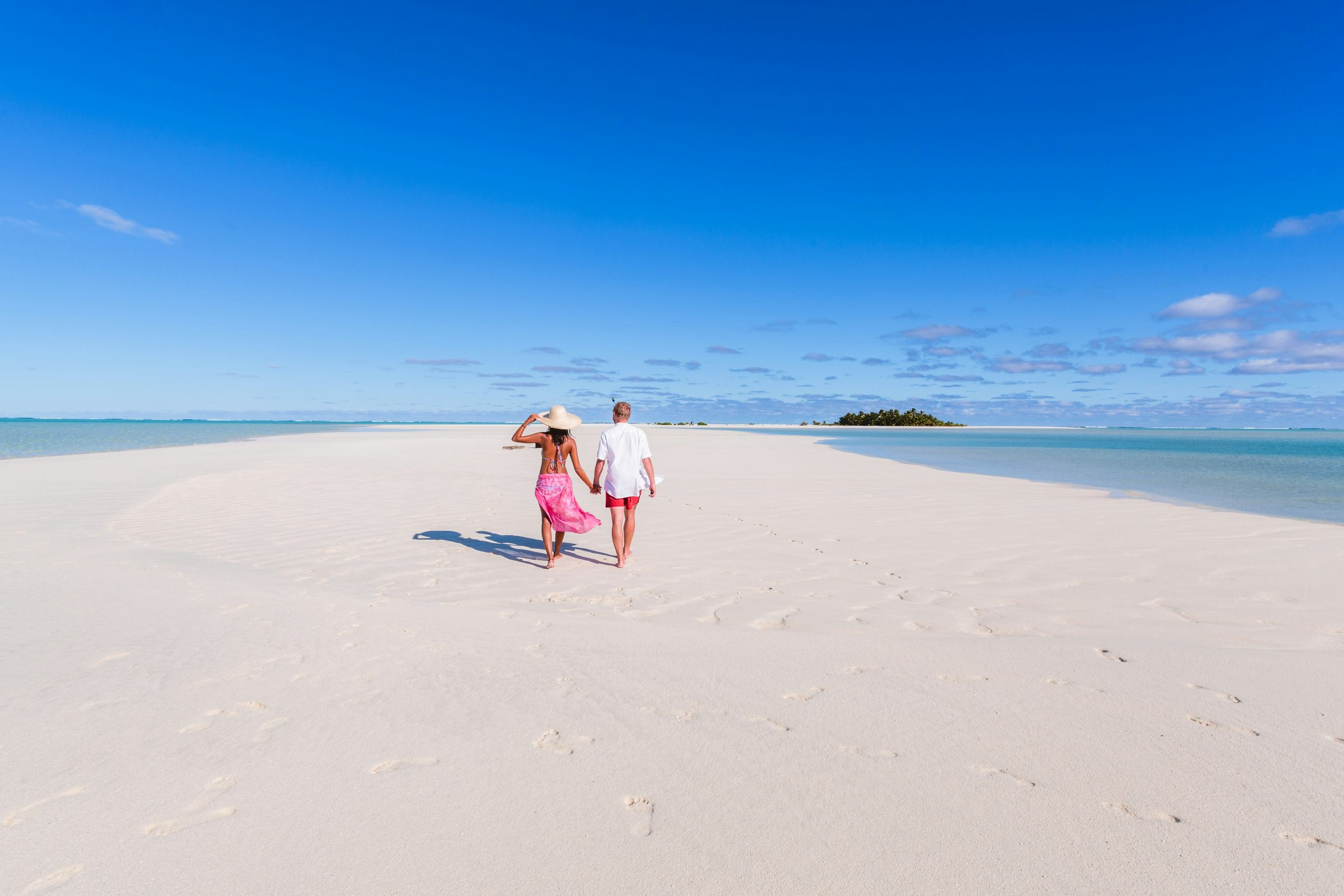 A man and a woman holding hands on a tropical beach