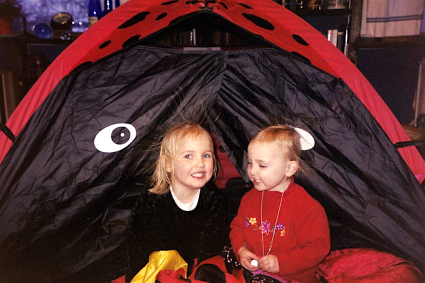 Two young girls play in a tent made to look like a ladybug, as their hair stands on end from the static; kids outdoor adventures