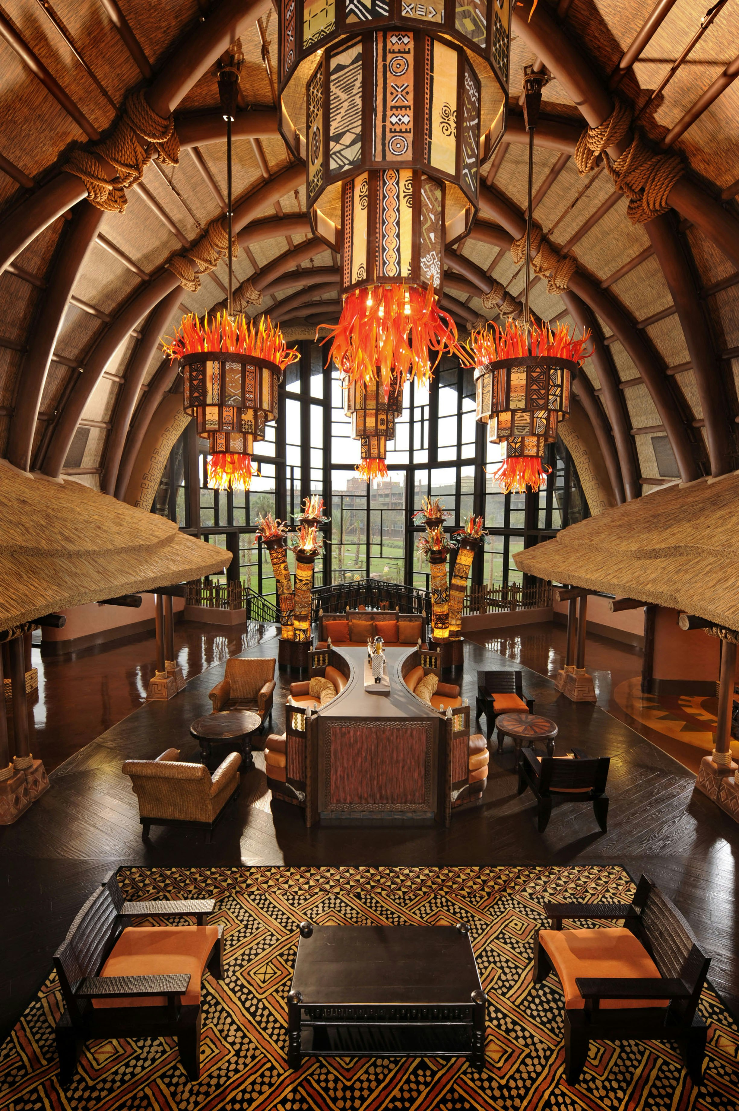 A hotel lobby with arching windows, Africa-inspired art, floor lamps and hand-carved wooden columns