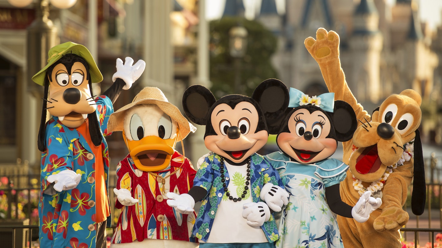 Costumed characters of Goofy, Donald Duck, Mickey Mouse, Minnie Mouse and Pluto stand together at a Disney park