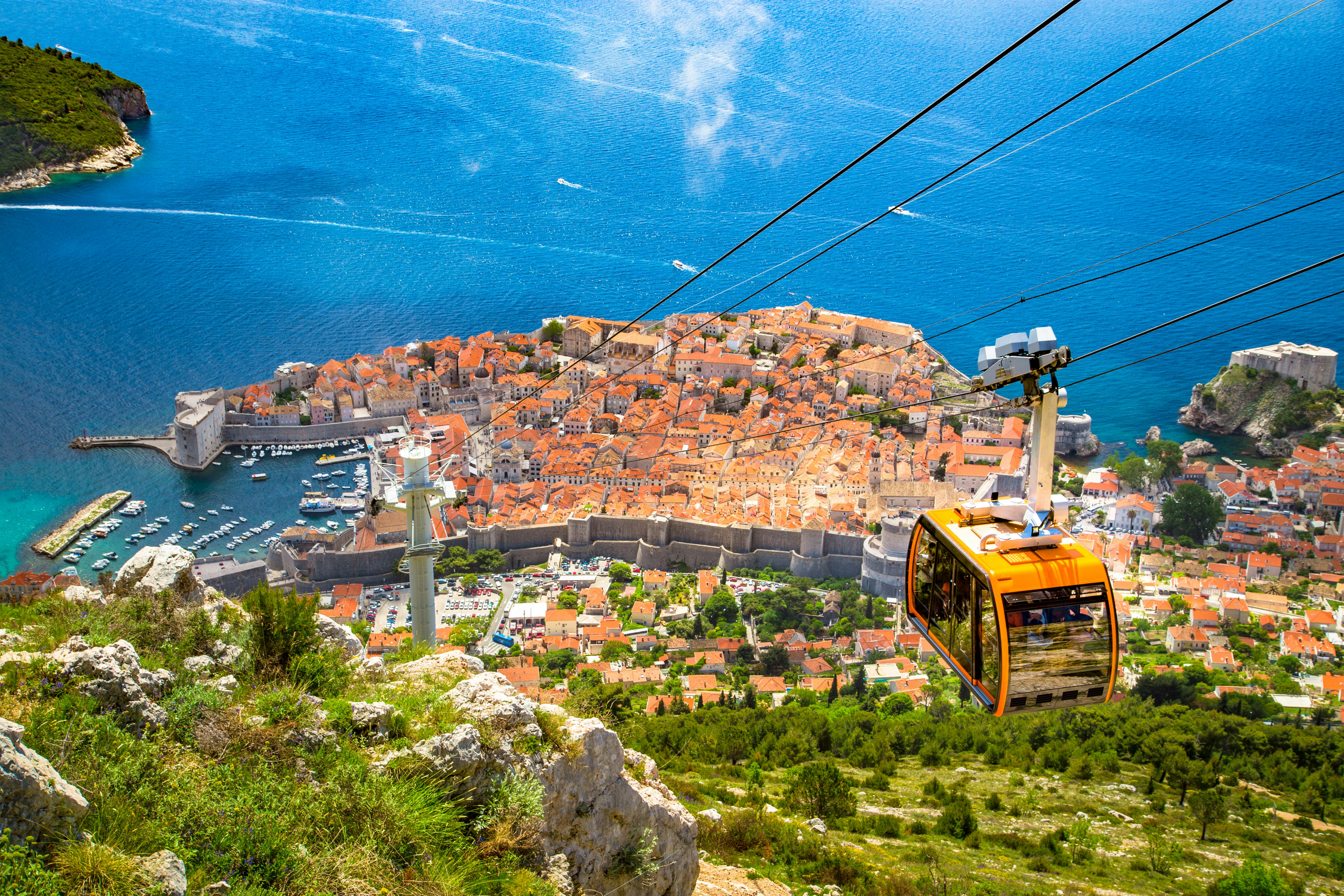 Aerial panoramic view of the old town of Dubrovnik with famous Cable Car on Srd mountain on a sunny day with blue sky and clouds in summer, Dalmatia, Croatia