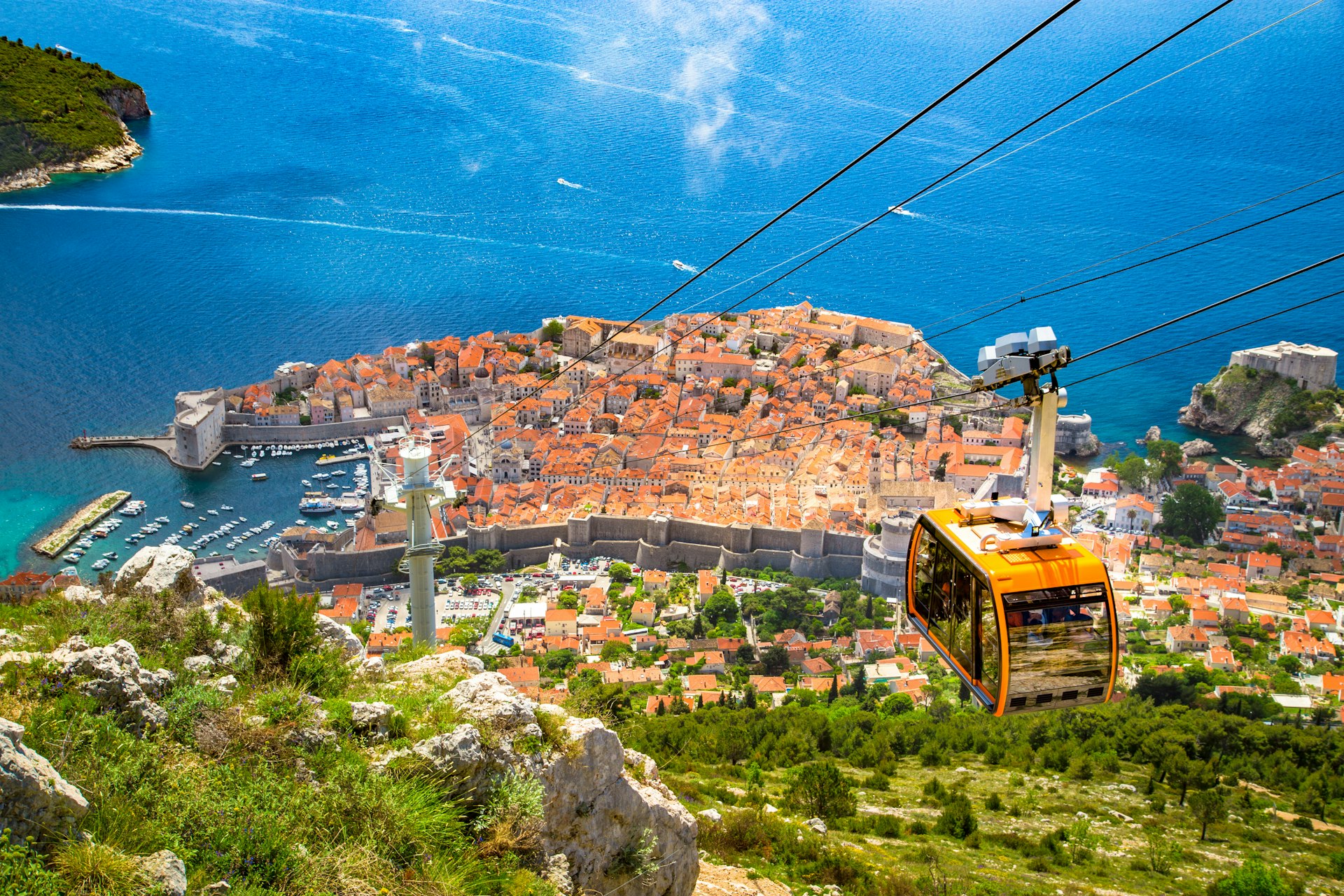 Aerial panoramic view of the old town of Dubrovnik with famous Cable Car on Srd mountain on a sunny day with blue sky and clouds in summer, Dalmatia, Croatia