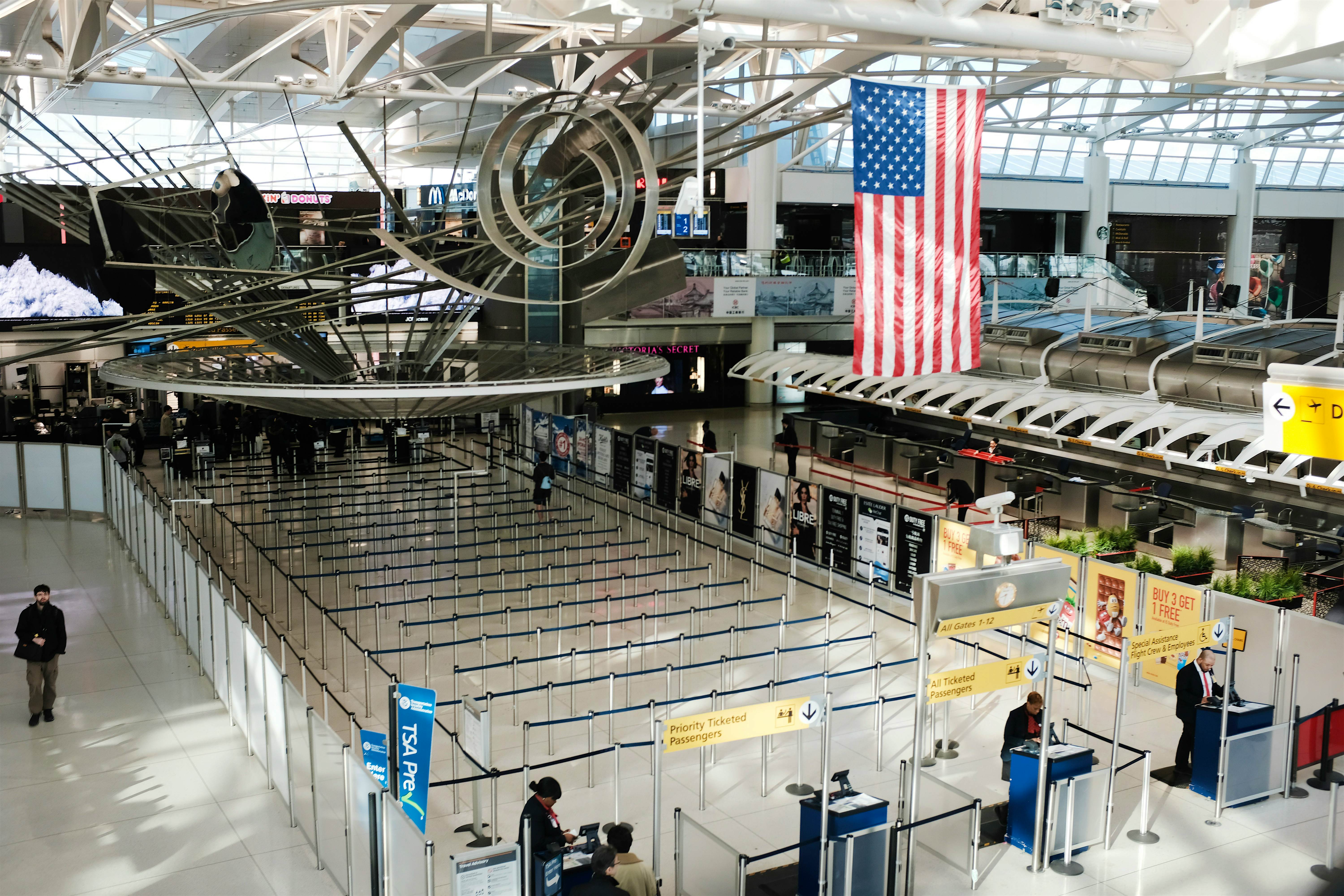 An empty line-up at an airport. An American flag and some installations hang overhead