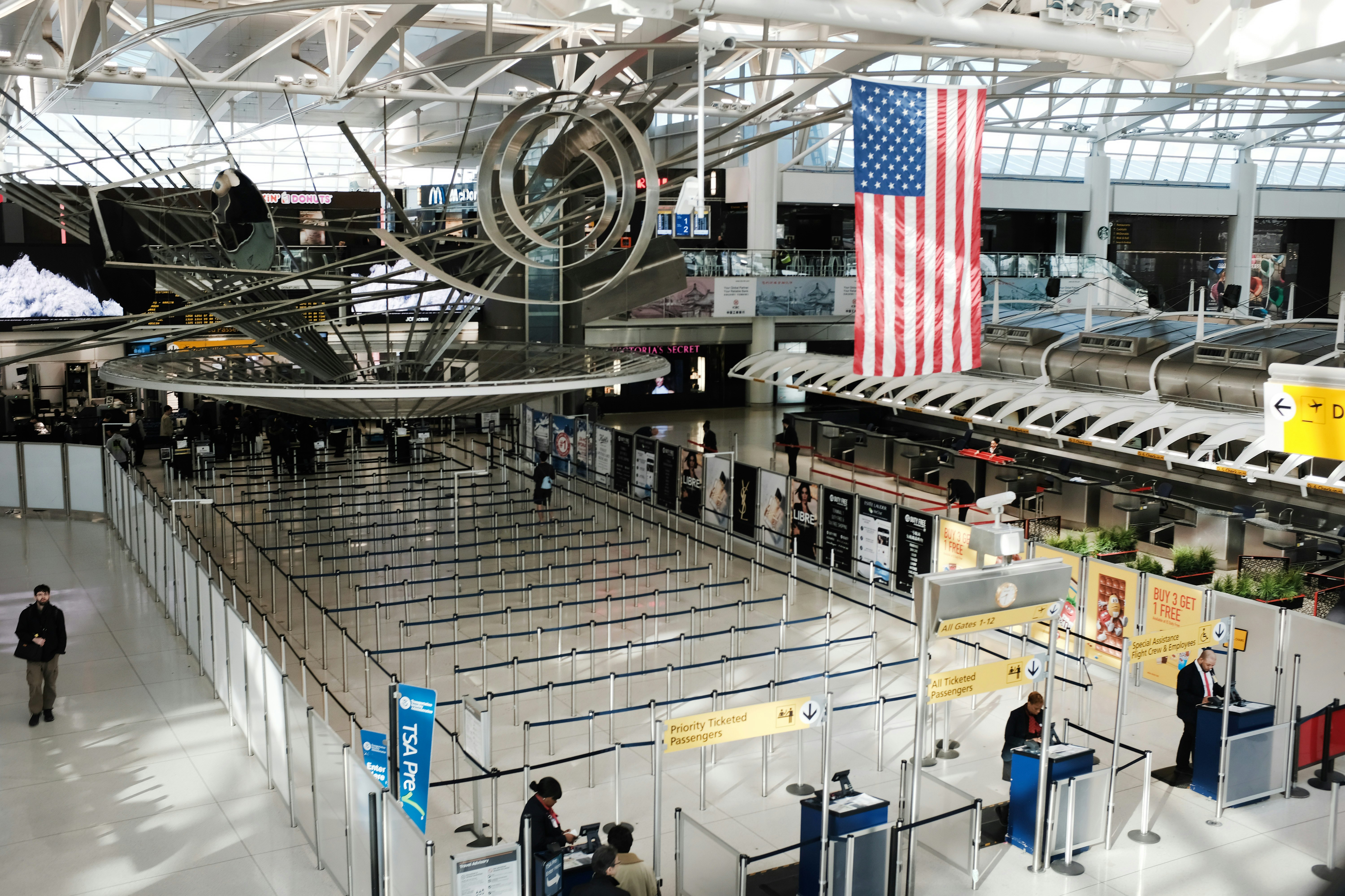 An empty line-up at an airport. An American flag and some installations hang overhead