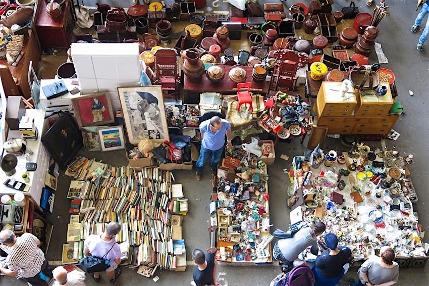 An overhead shot of tables, ledges and floor spaces completely covered in items for sale, including books, baskets, electronics, vases and trinkets.