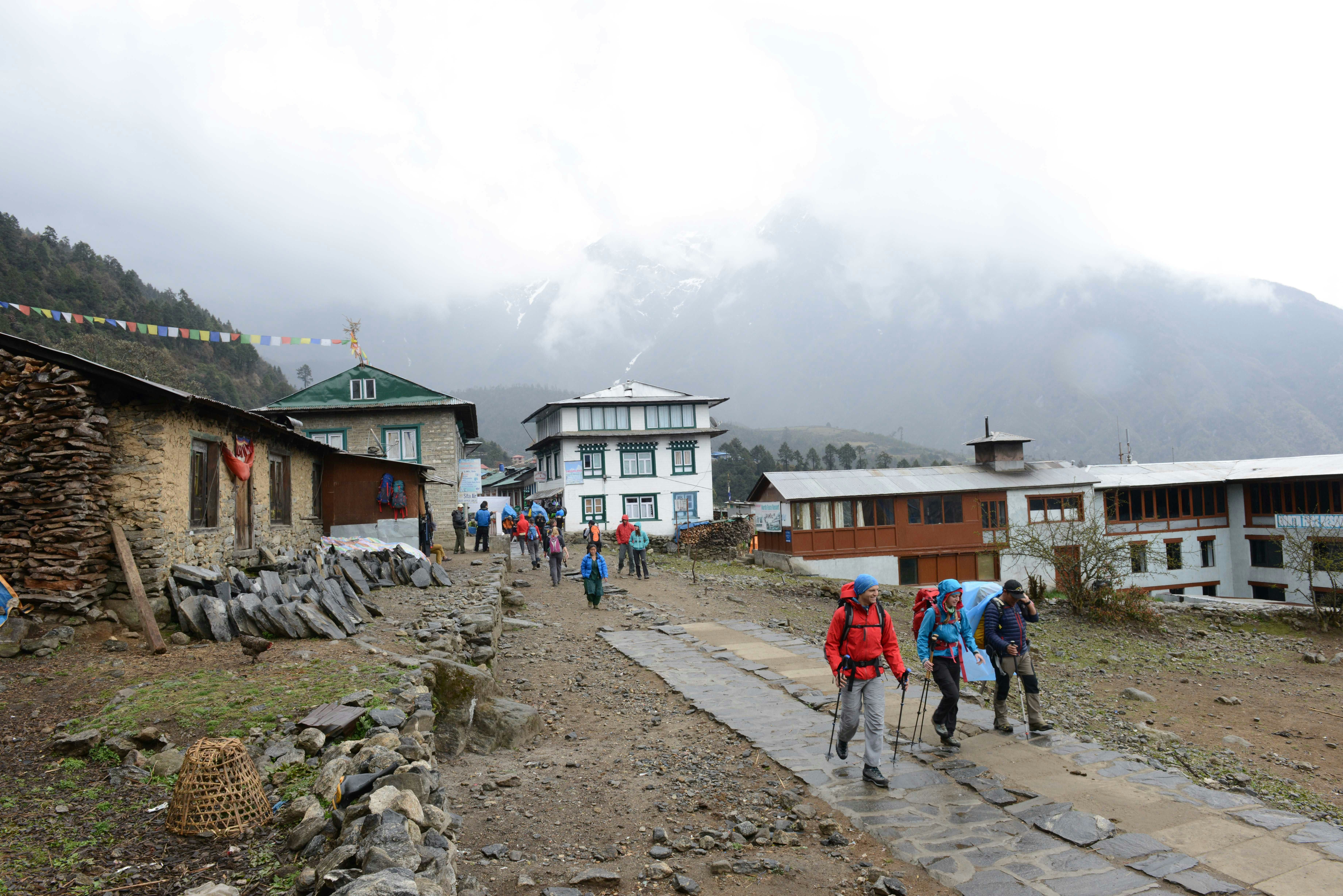 Hikers depart from the town of Lulka, Tibet with trekking poles in hand on a cobbled street