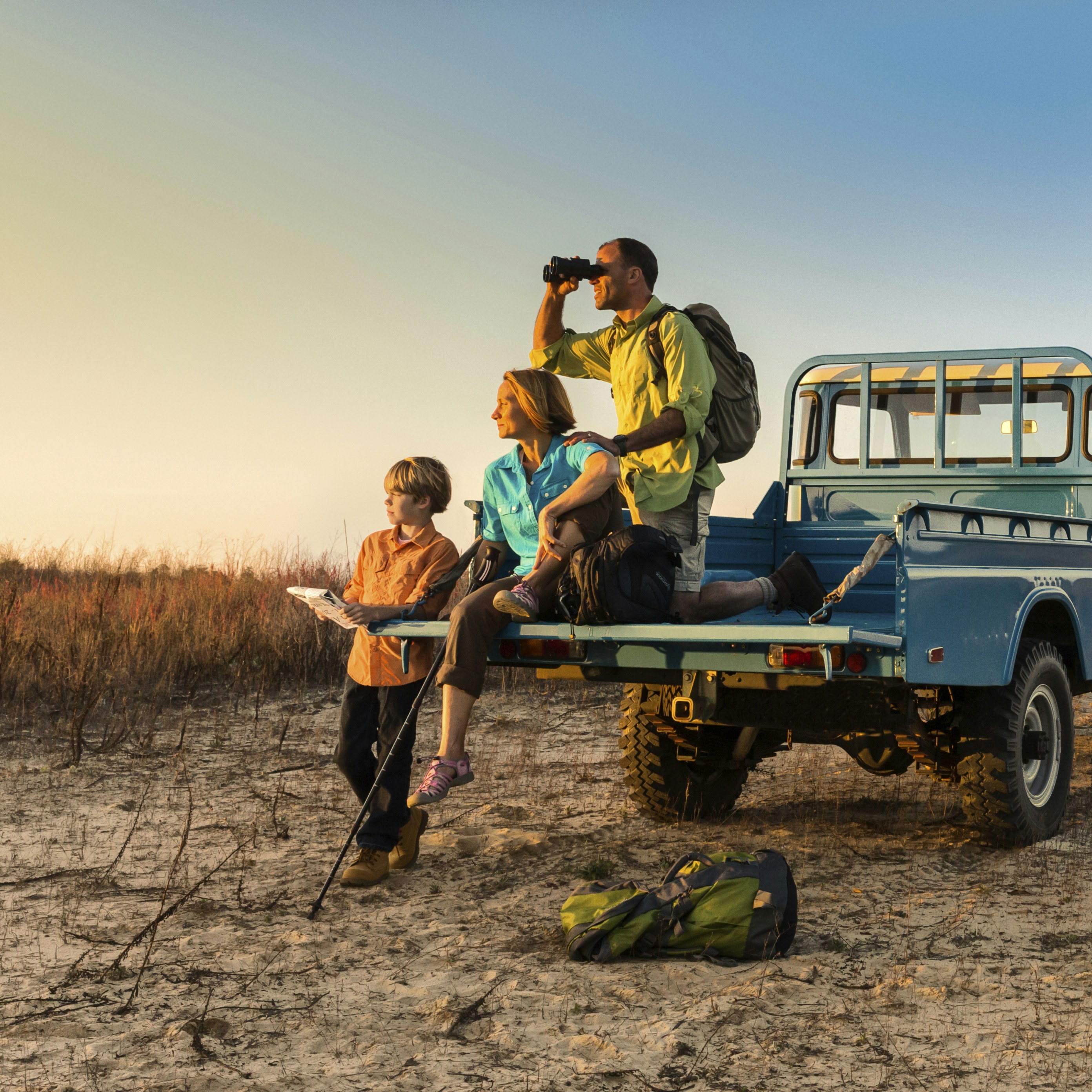 A family sits near the back of a safari truck, looking into the distance