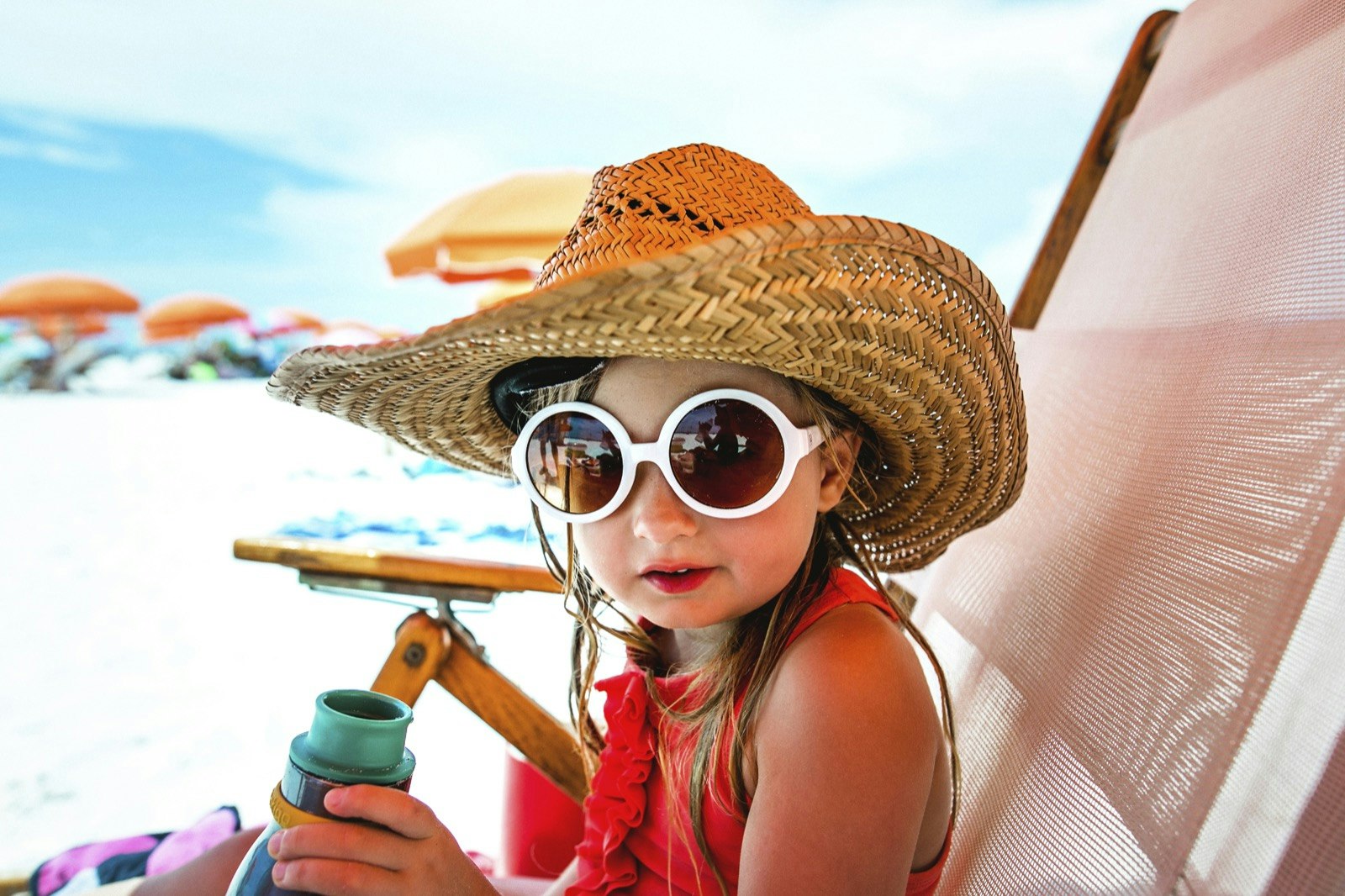 Young girl with large sunglasses sits in a lounge chair on the beach in Clearwater, Florida