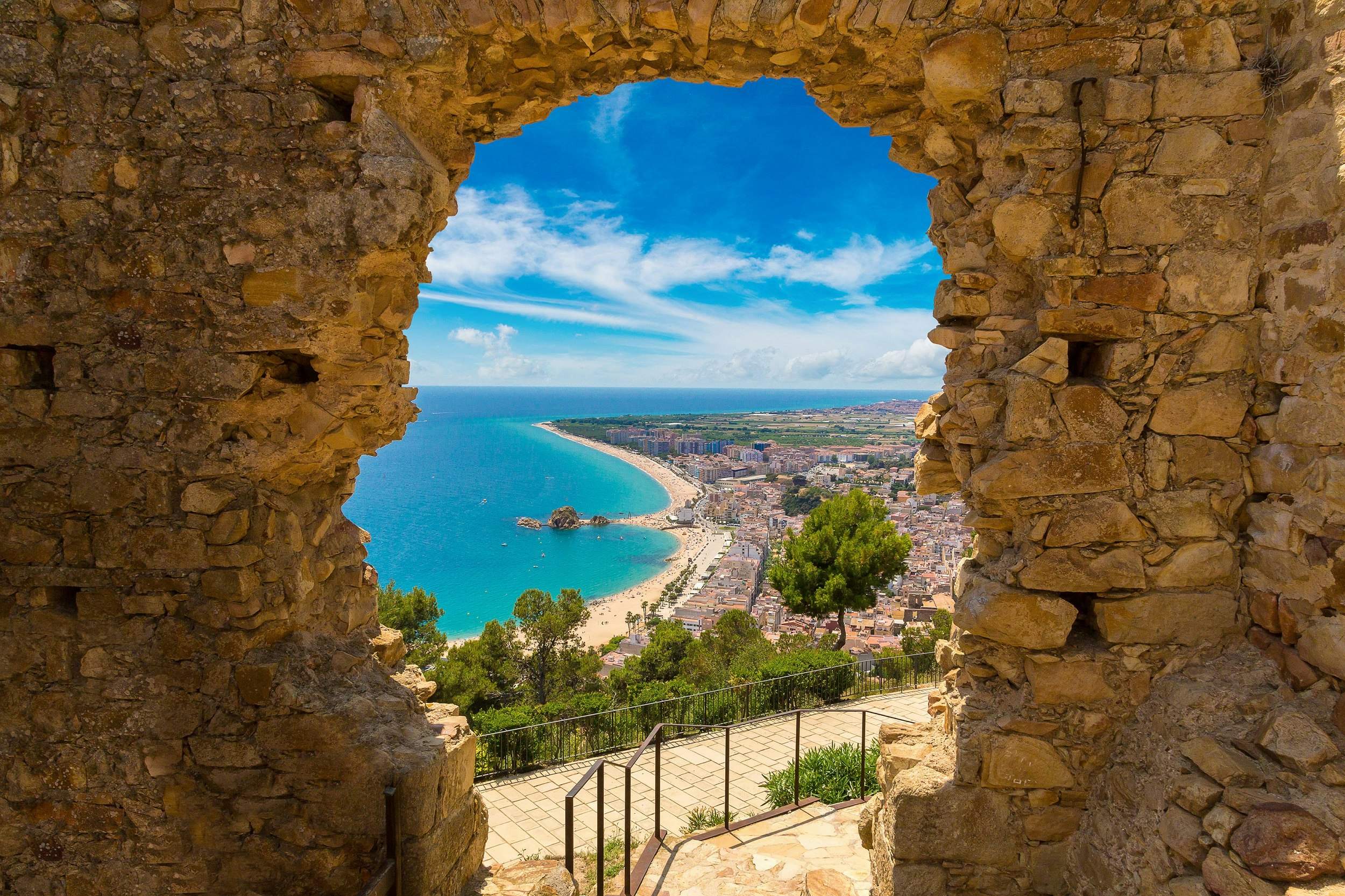 And aerial image of Blanes beach in the distance, through a stone door of St John Castle high above town.