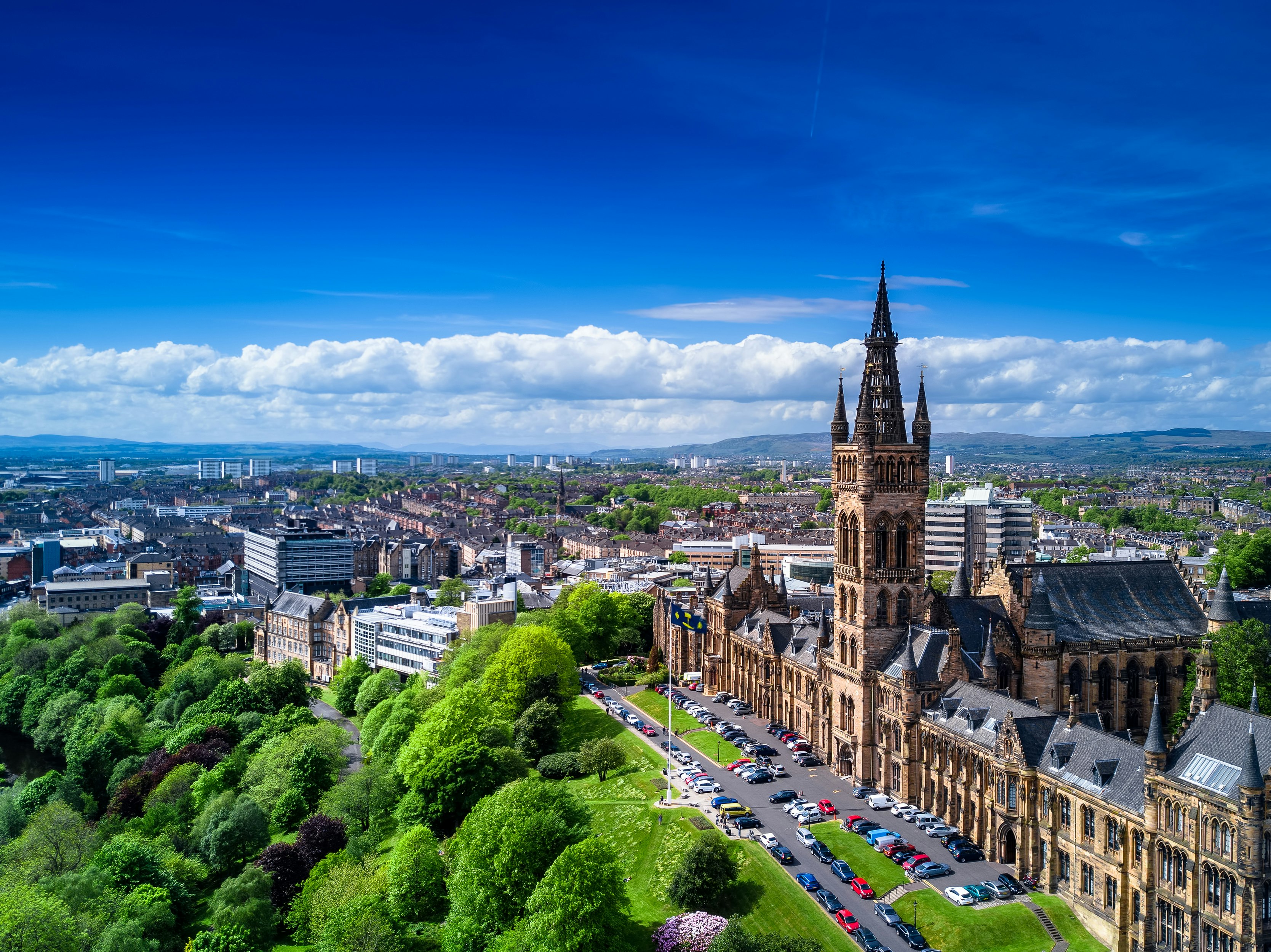 An elevated view of Glasgow; Glasgow University and its green surrounds take up most of the frame, while the industrial city stretches beyond.