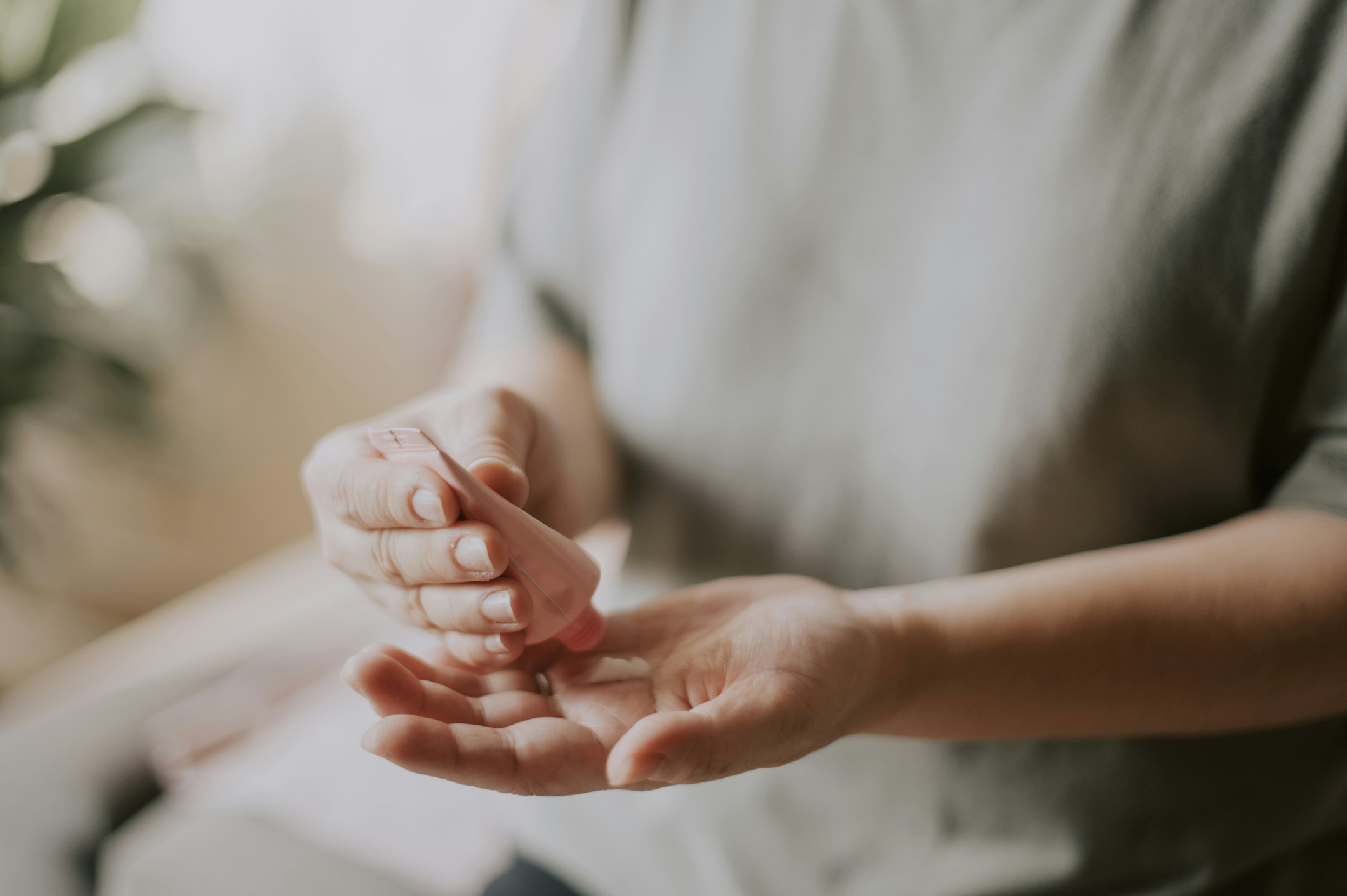 A woman rubs cream into her hands, on one of which is a golden wedding band