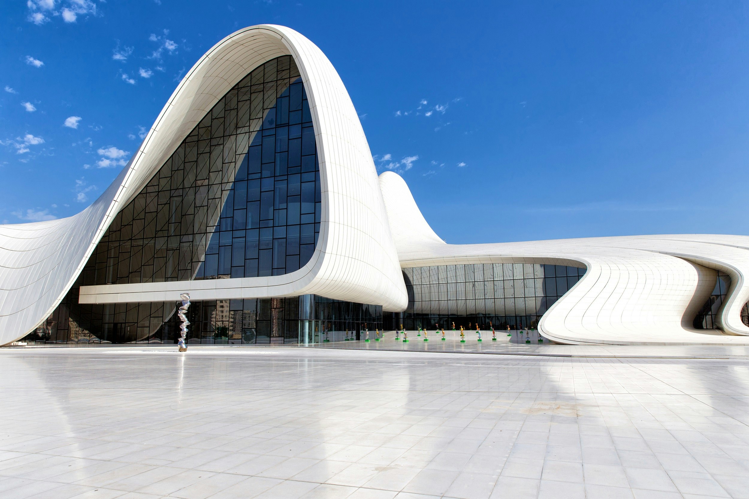 A large, white, curved building with sloping sides covered in smooth white tiles.