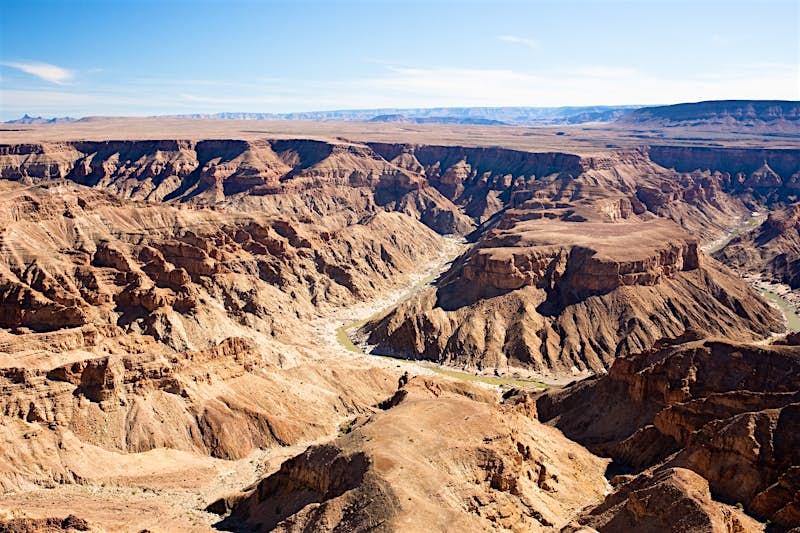 A huge horseshoe bend in the Fish River cuts down through the canyon of the same name; the layers of the rock are clearly visible, and the plateau atop extends to the horizon. Everything is brown in tone.