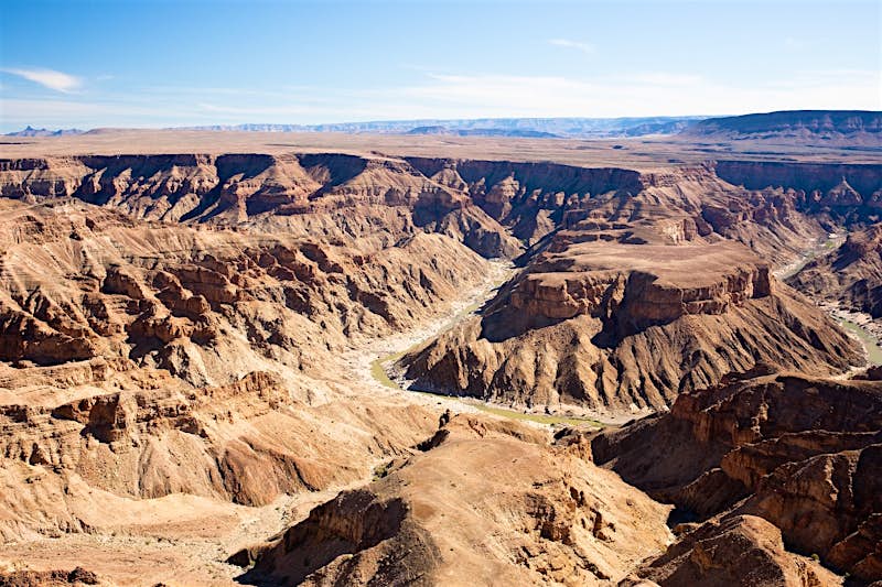 hiking-fish-river-canyon-namibia.jpg A huge horseshoe bend in the Fish River cuts down through the canyon of the same name; the layers of the rock are clearly visible, and the plateau atop extends to the horizon. Everything is brown in tone.