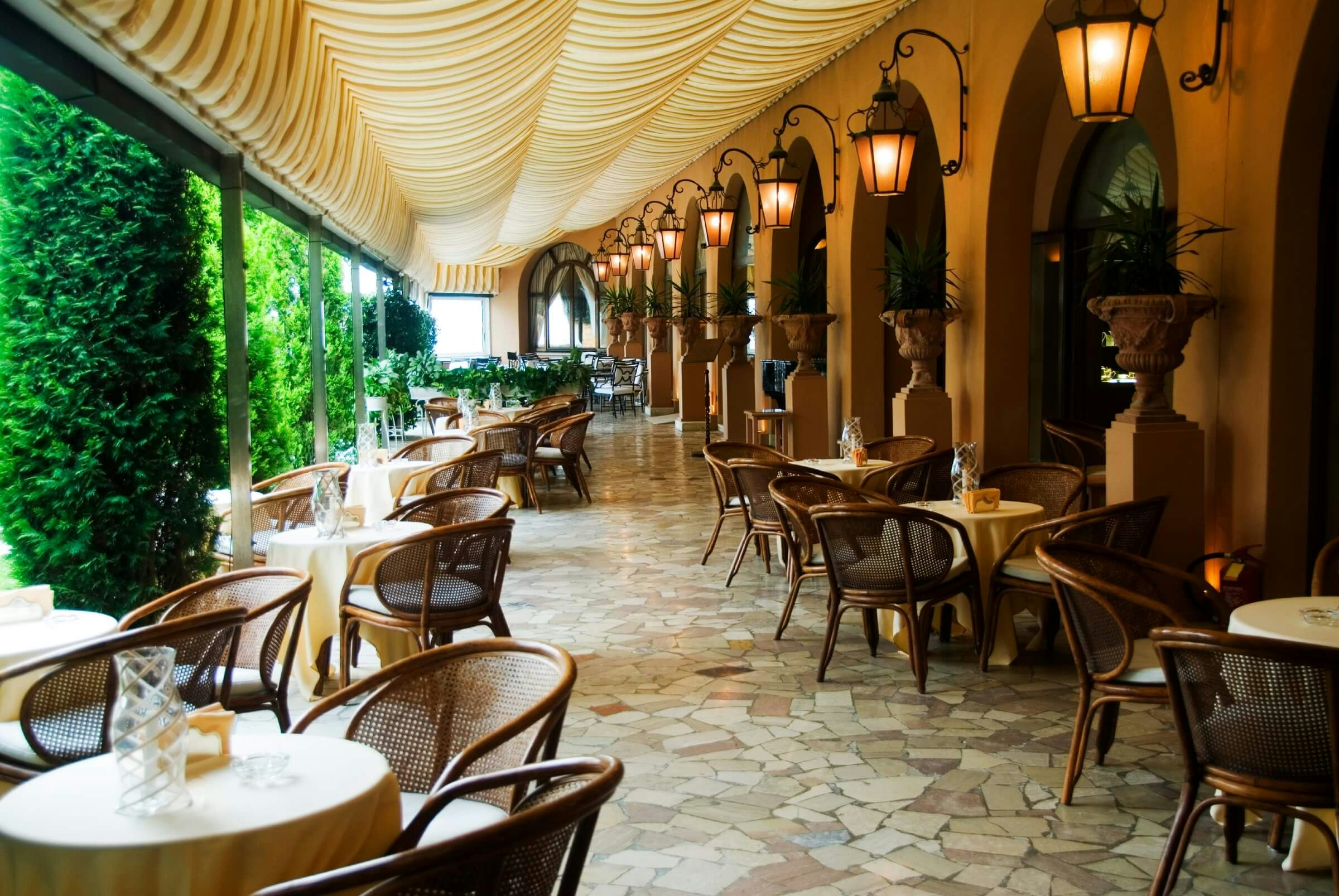 A covered outdoor terrace dining room, empty of people.