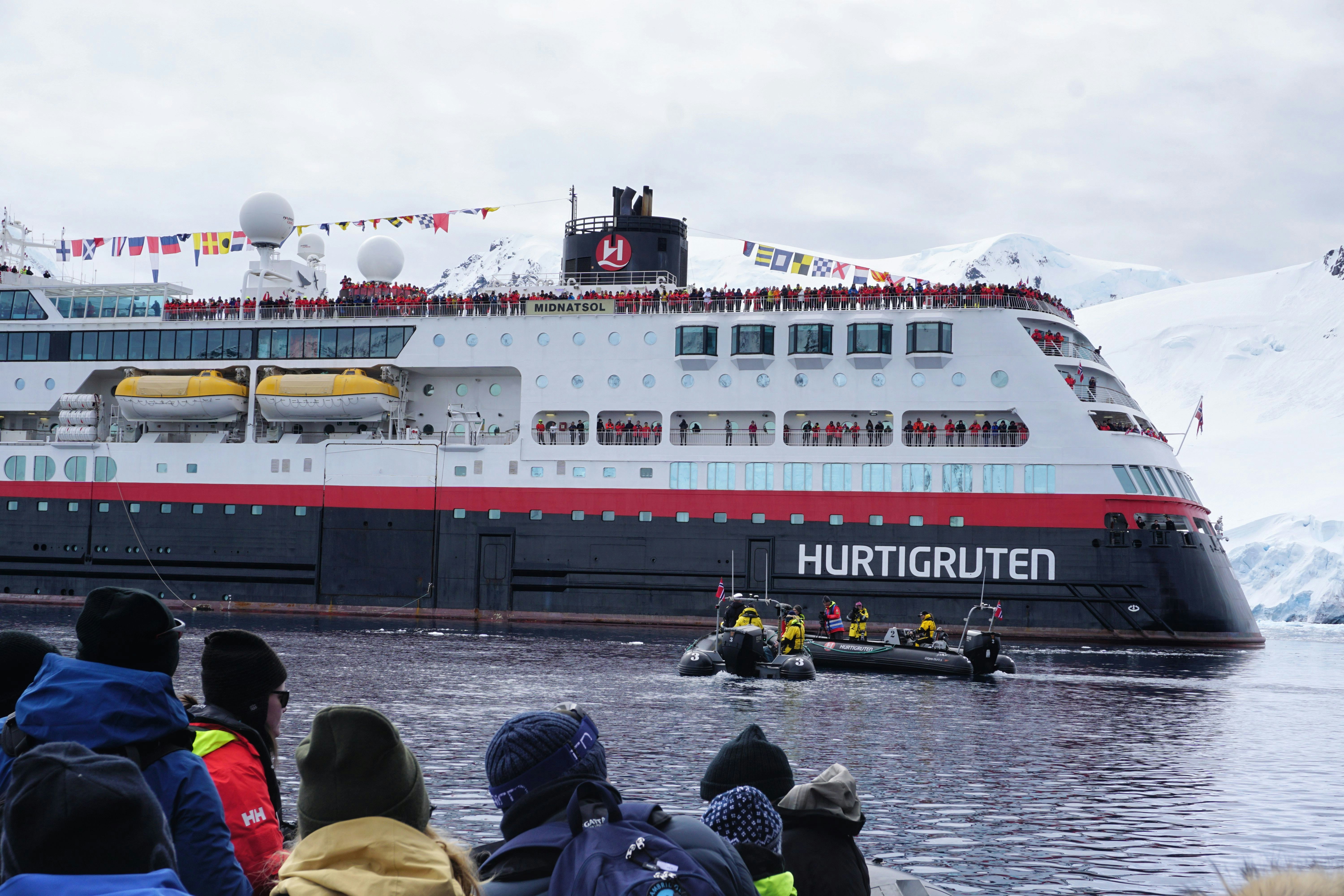 A crowd watches as a black Zodiac boat approaches the Hurtigruten MS Roald Amundsen for its naming ceremony in Antarctica