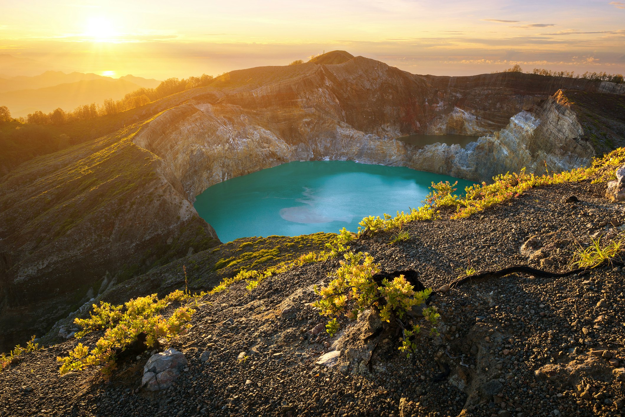 A volcanic crater is filled with blue water surrounded by a mountain. 