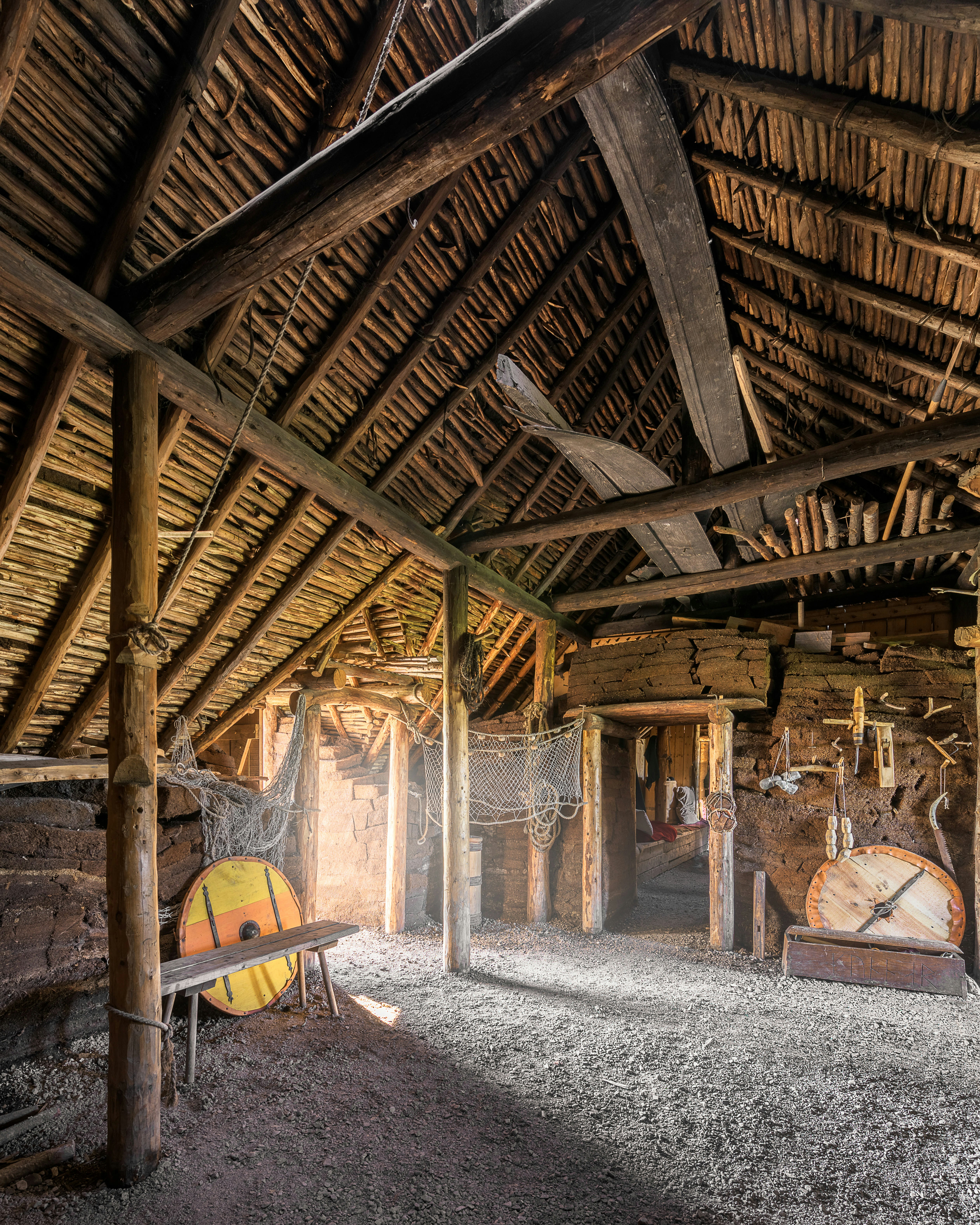 Interior of a wooden structure with a dirt floor and circular shields