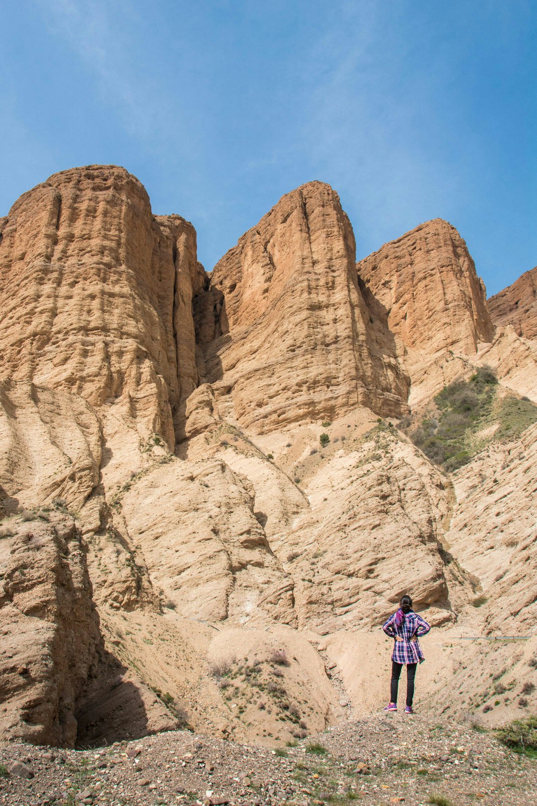 A lone woman stands in front of a dramatic rock formation in Iran